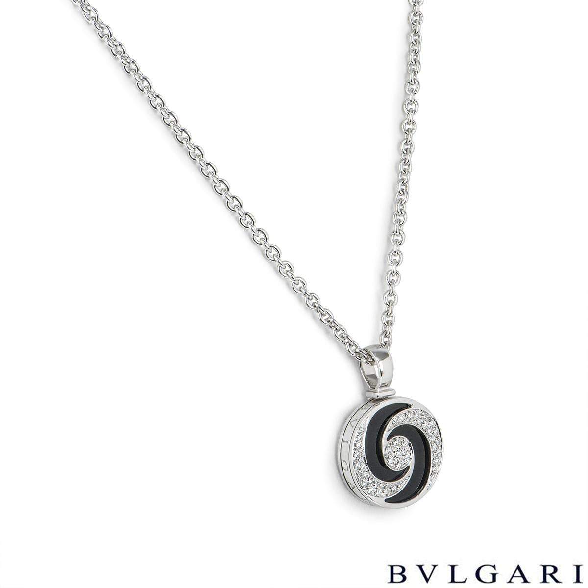 An 18k white gold and stainless steel pendant by Bvlgari from the Optical Illusion collection. The pendant consists of a rotating disc that measures 2.3cm in width and spins in both a clockwise and anti-clockwise motion. It features an onyx inlay