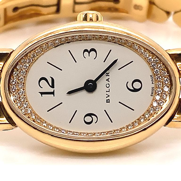 Authentic Bvlgari Ovale ladies watch in 18k yellow gold, Ref. OV 27 G. This stunning watch features a 20mm 18k gold case with closed solid snap back. The watch has a Pave' set diamonds inner bezel, a white dial with back Arabic and stick hour
