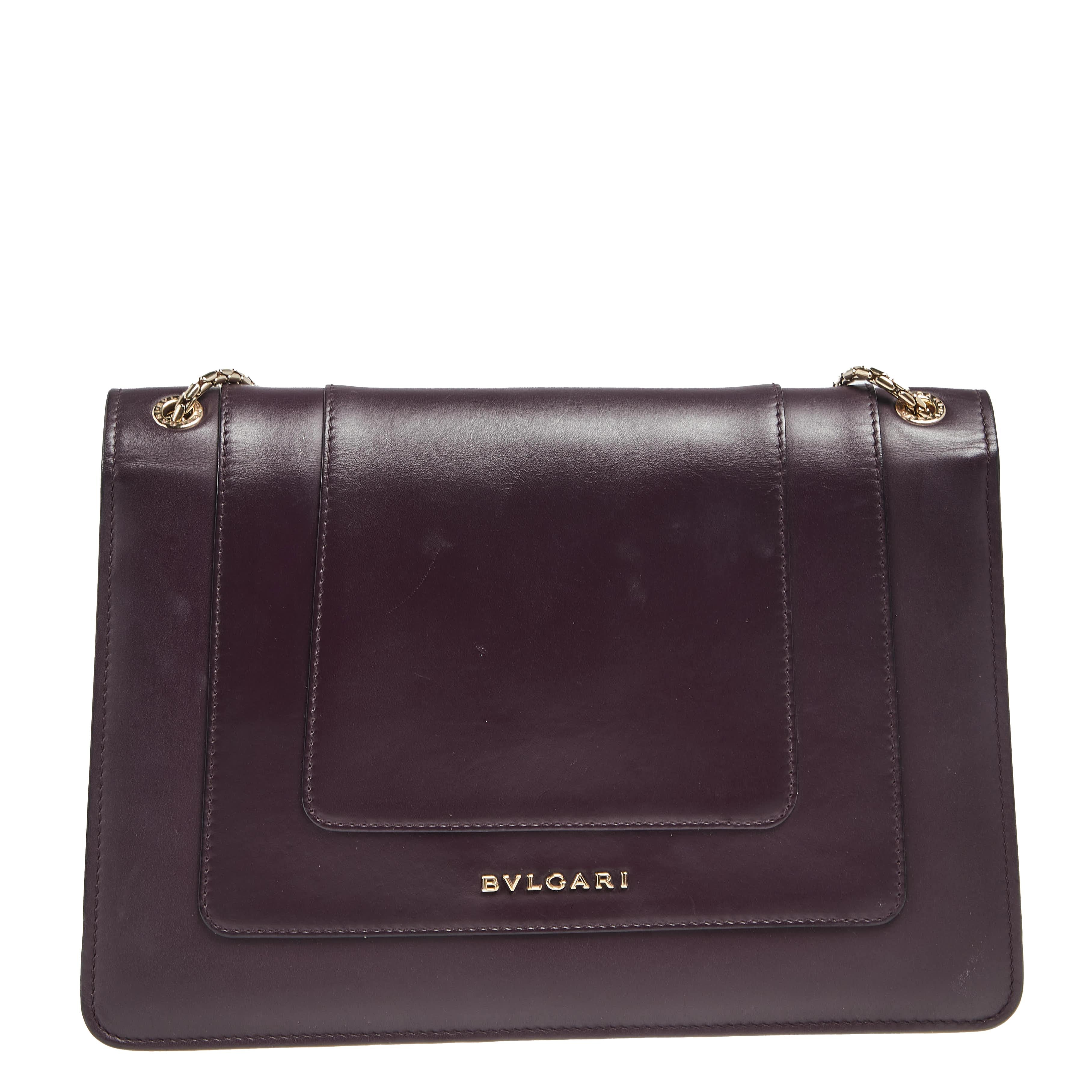 Dazzle the eyes that fall on you when you swing this stunning Bvlgari creation. Crafted from leather in a breathtaking plum hue, the shoulder bag is styled with a flap that has the iconic Serpenti head closure. The bag has a spacious fabric interior