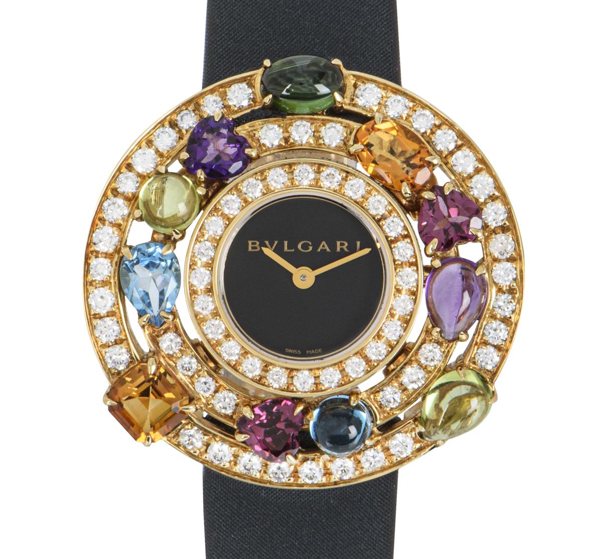 A stunningly rare multi-gem ladies 36mm  Astrale wristwatch, crafted in yellow gold by Bvlgari, featuring a black dial. Complimenting the dial is 66 round brilliant diamonds and is further set with multi gems that range from dark green tourmaline,