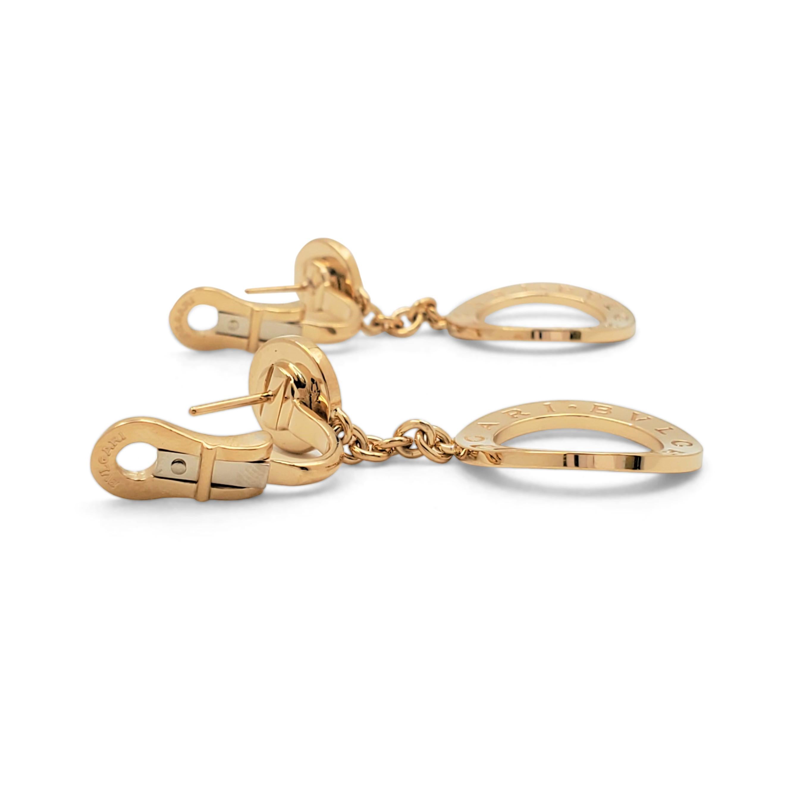 Authentic Bvlgari earrings from the 'Reva' collection. Crafted in 18 karat yellow gold, the earrings are comprised of an open disc engraved BVLGARI-BVLGARI on both sides and one smaller disc set with a shimmering round mother-of-pearl accent. Signed