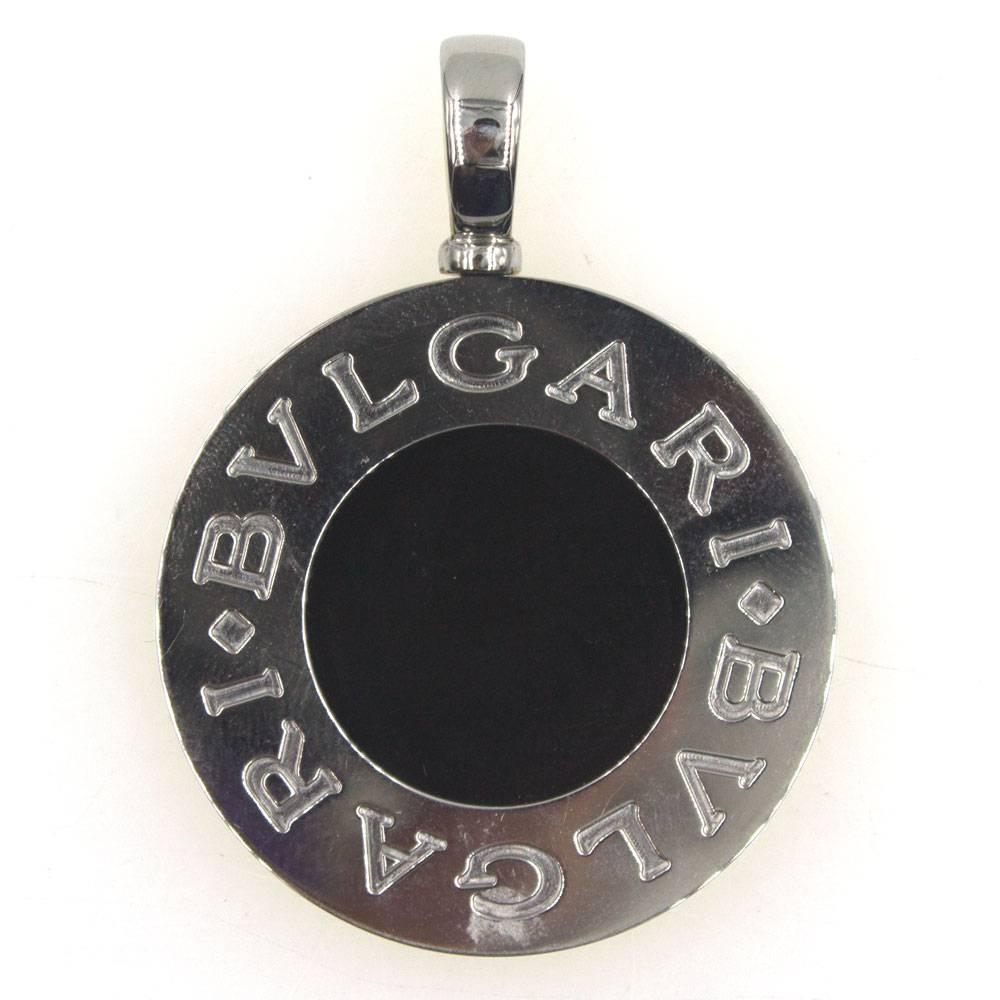 This stylish reversible Bvlgari pendant is fashioned in 18 karat yellow gold and stainless steel. The yellow gold side features lapis lazuli gemstone, and the stainless steel side is matched with onyx. Measuring 35mm in diameter, the pendant is