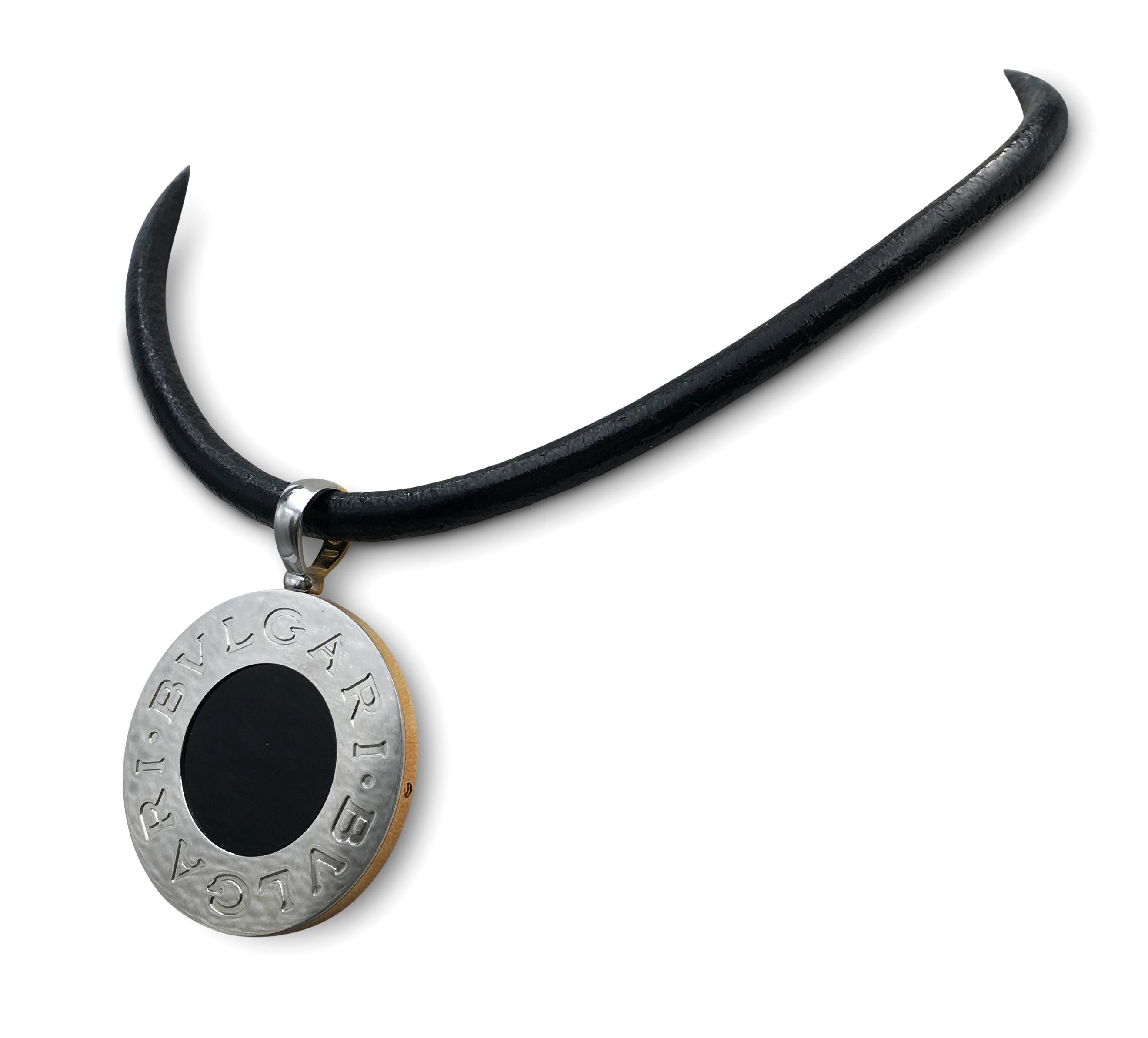 Authentic Bvlgari necklace features an iconic Bvlgari reversible coin pendant. One side of the coin is crafted in 18 karat yellow gold and set with a mother-of-pearl center while the reverse has a steel coin with an onyx center. The coin is strung