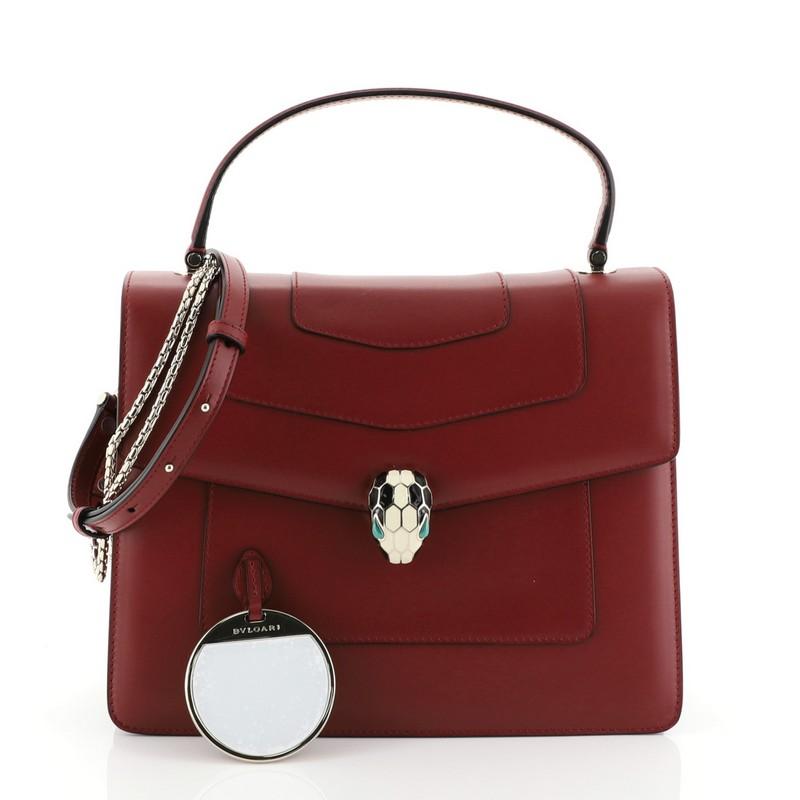 This Bvlgari Serpenti Forever Top Handle Bag Leather Medium, crafted from red leather, features a leather top handle, Serpenti head closure with malachite eyes, and gold-tone hardware. Its flap opens to a pink fabric interior with side slip pocket.