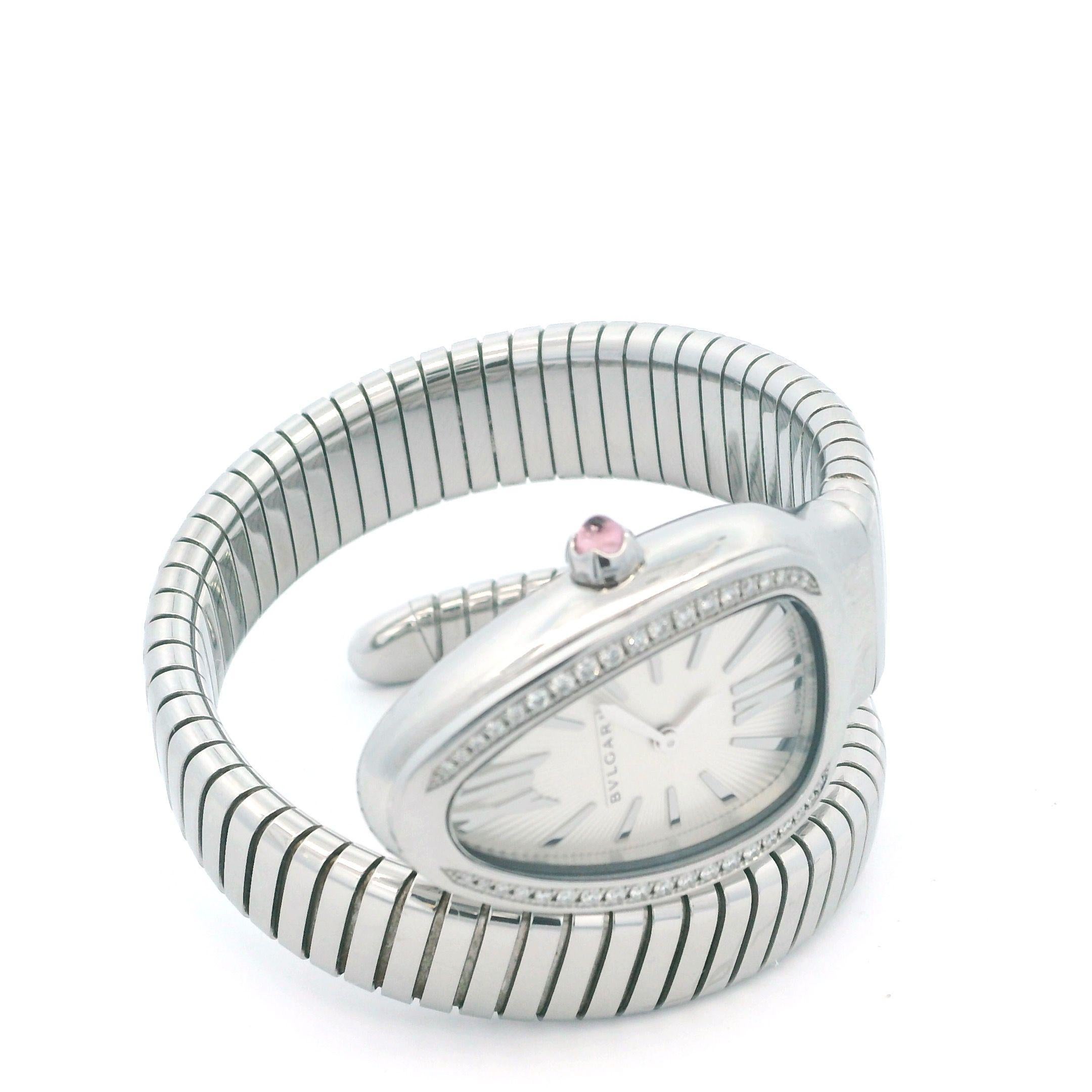 La Bvlgari Serpenti en acier inoxydable présente un cadran opalin argenté avec traitement guilloché soleil et index. Couronne sertie d'une rubellite rose taillée en cabochon. Boîtier incurvé serti de diamants. Design/One iconique avec bracelet
