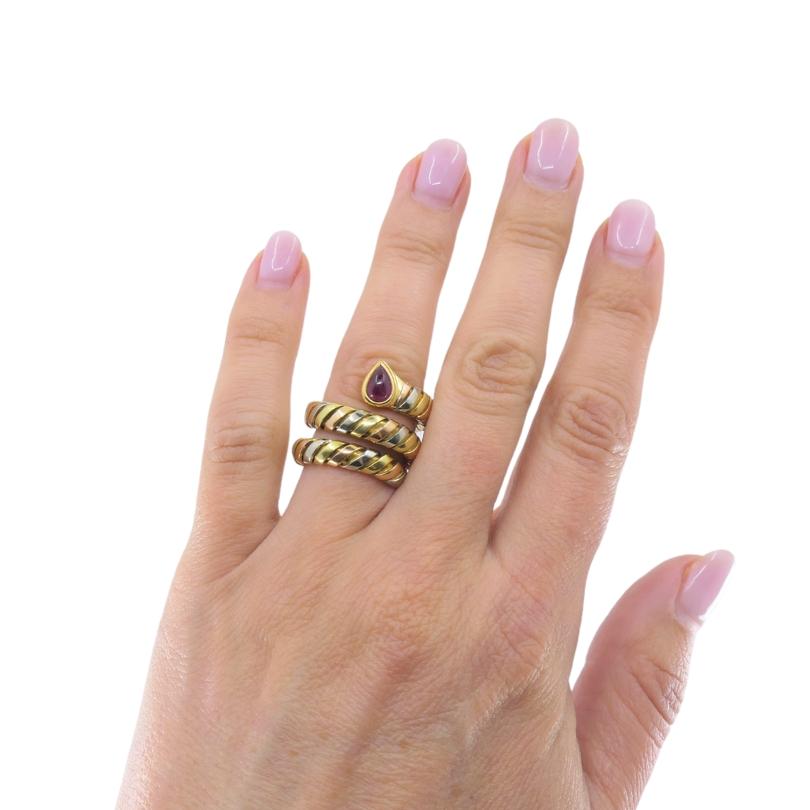 The Bvlgari Serpenti Tubogas Gold Ruby Ring is crafted in 18k gold, features alternating sections of yellow, rose, and white gold, creating a visually dynamic and luxurious tricolor effect. The ring is formed in Bvlgari’s signature coiled,
