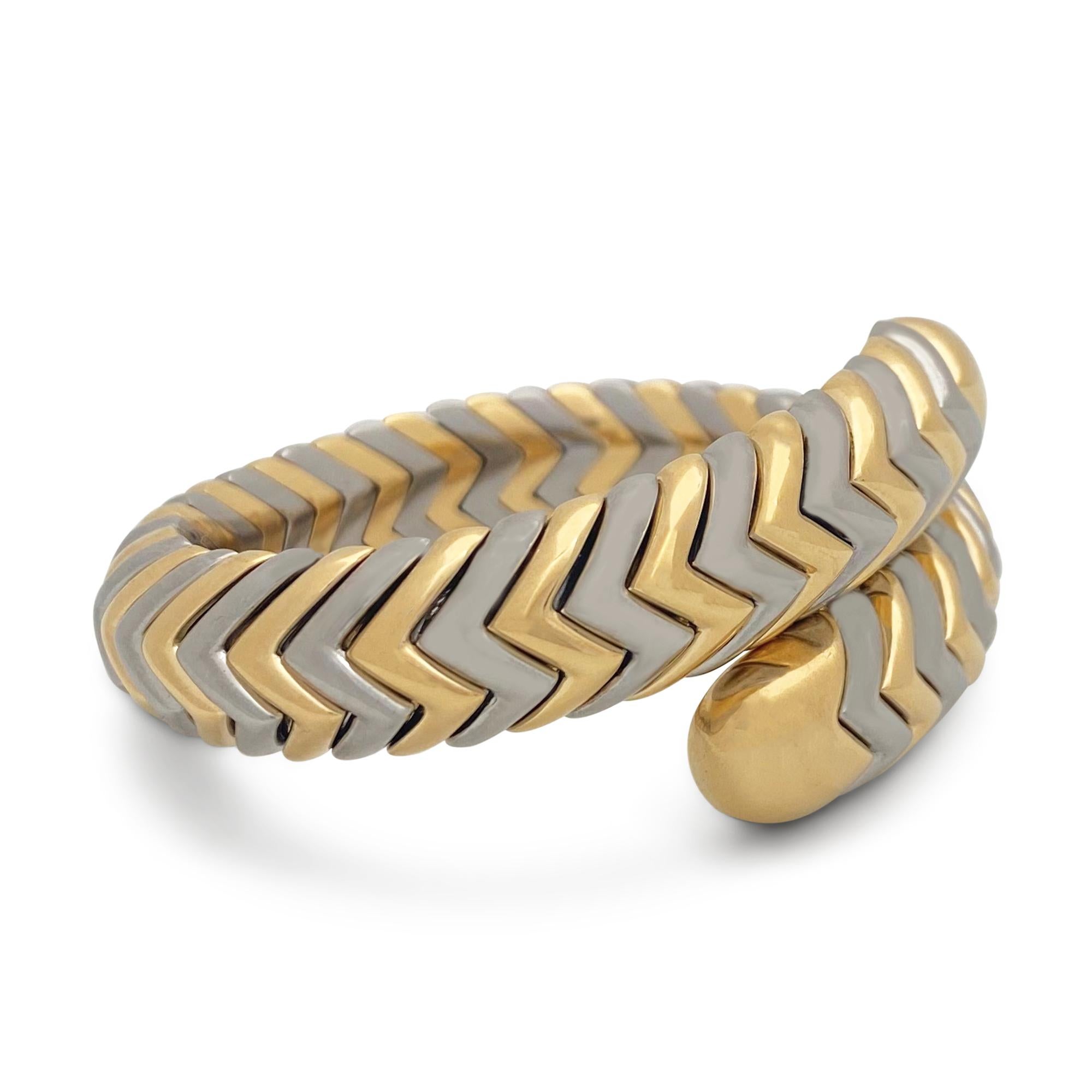 Authentic Bvlgari Spiga bracelet crafted in 8 karat yellow gold and stainless steel. The iconic Spiga pattern is represented here in a two row bypass design. The internal circumference is 5 1/2 inches and the bracelet will fit up to a 6-inch wrist. 