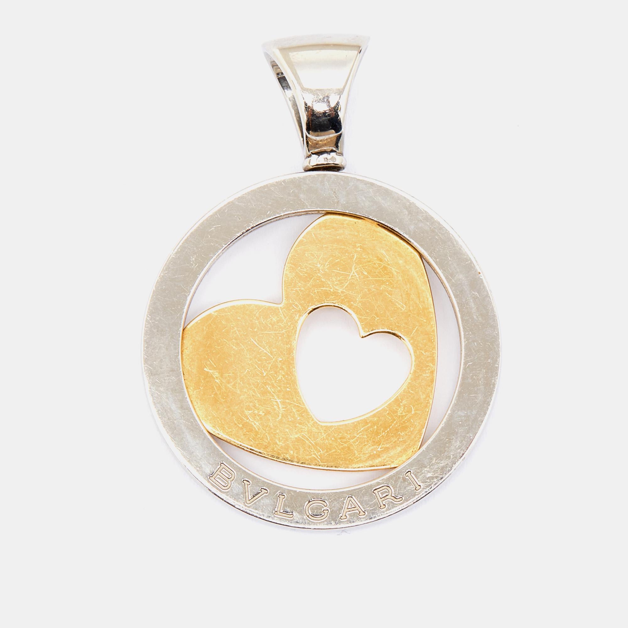 Weighing 11.70 grams, this Tondo Heart pendant from Bvlgari comes with a bail to loop into a necklace chain/cord. It has been crafted from stainless steel and 18k yellow gold.

