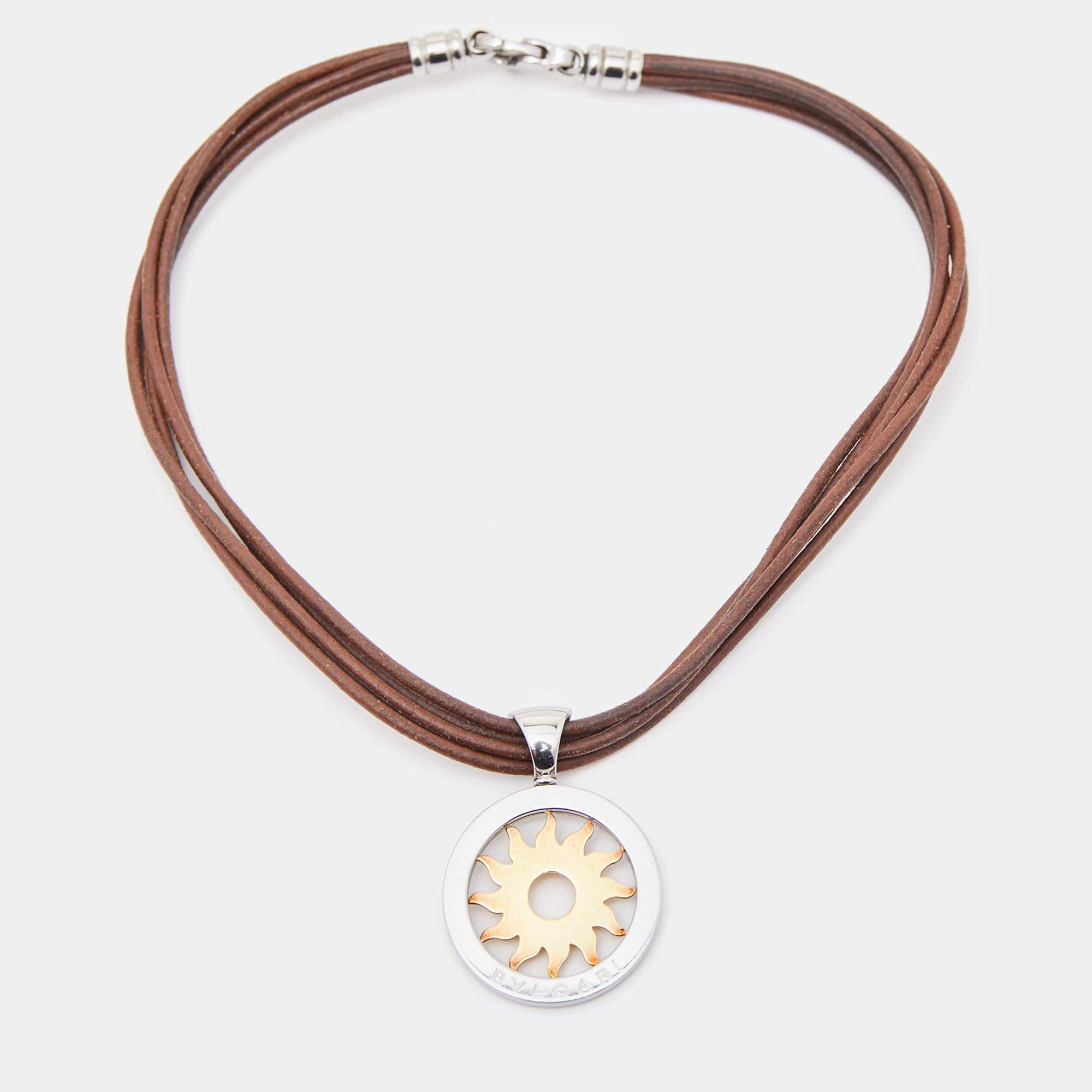 The Bvlgari Tondo necklace seamlessly blends stainless steel and 18k yellow gold, forming a radiant pendant. A leather cord adds a touch of luxury. The design exudes modern elegance, combining materials harmoniously for a versatile accessory that