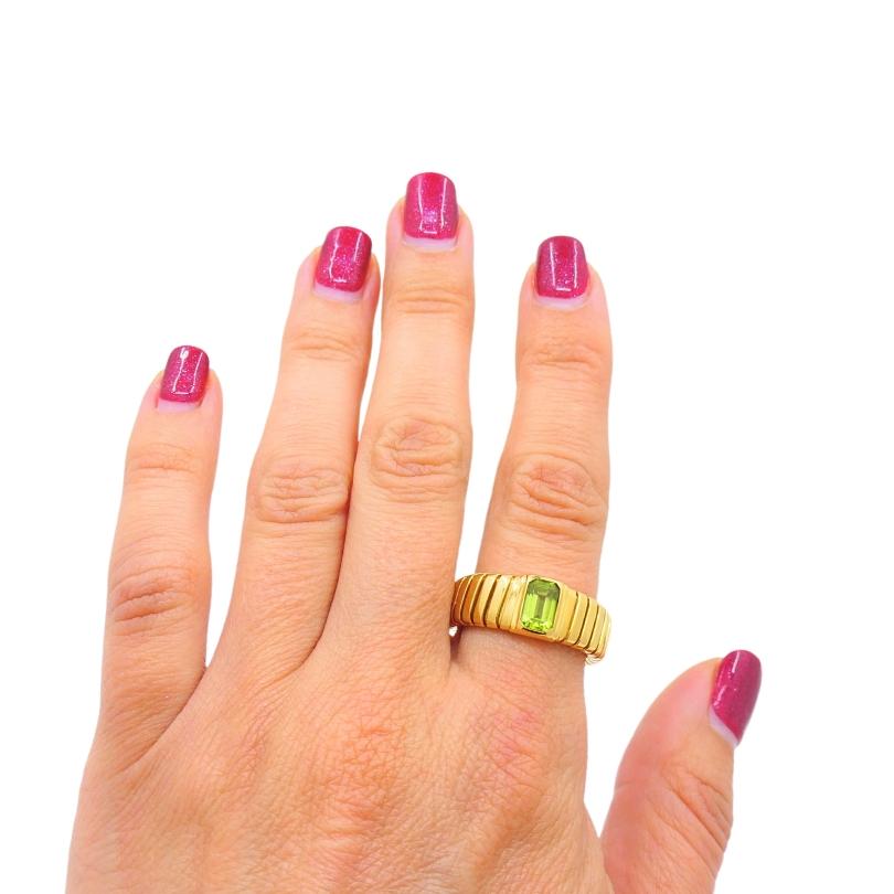 This exquisite Bvlgari Tubogas ring is crafted from 18k yellow gold, showcasing the brand's iconic Tubogas technique. The ring features a stunning peridot gemstone, adding a vibrant green hue to its design.  The ring's design is both elegant and