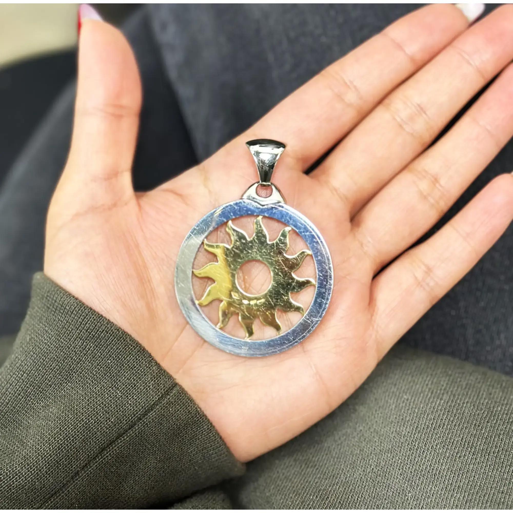This stunning Bvlgari two tone Tondo pendant is predominantly set with a center sun motif made of 18K yellow gold and surrounded with logo engraved stainless steel. Pendant diameter: 1.8 inches. Thickness: 3.5mm. Total weight: 23.20 grams. No chain