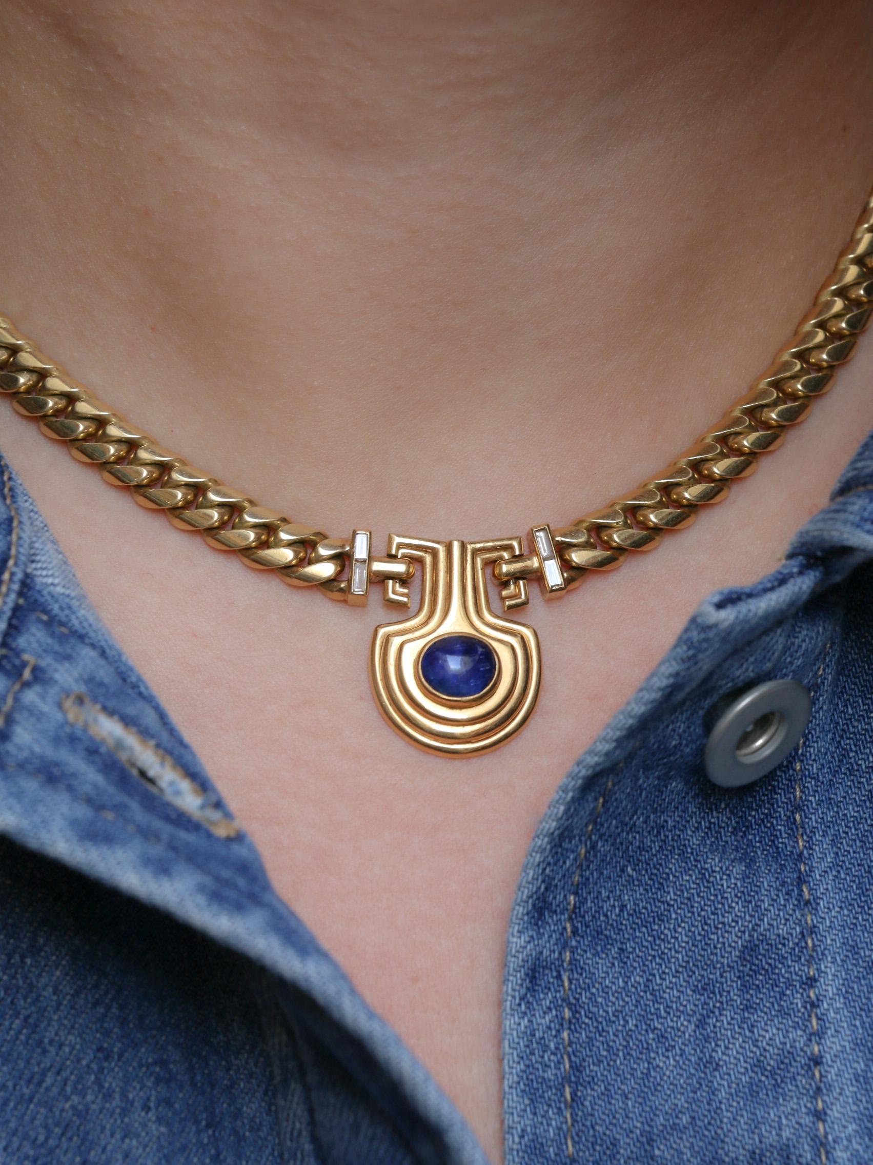 18Kt (750°/°°) yellow gold necklace featuring a gourmette chain and a pendant with a 2.55-carat (8.3 x 6.7 x 4.2 mm) royal-blue cabochon sapphire set in a gadrooned amphora. Open frosting and fractures are visible on the back of the cabochon.