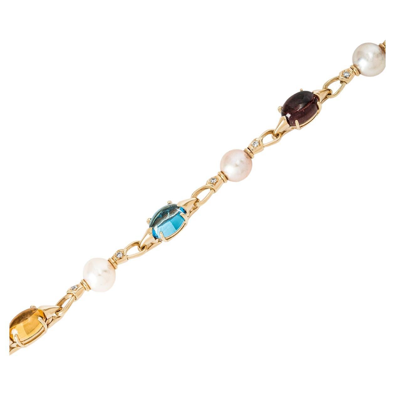 An alluring 18k yellow gold multi-gemstone, pearl and diamond bracelet by Bvlgari from the Allegra collection. The bracelet comprises of 2 cabochon cut topaz displaying a vibrant blue hue, 1 cabochon cut tourmaline displaying a medium-dark burgundy