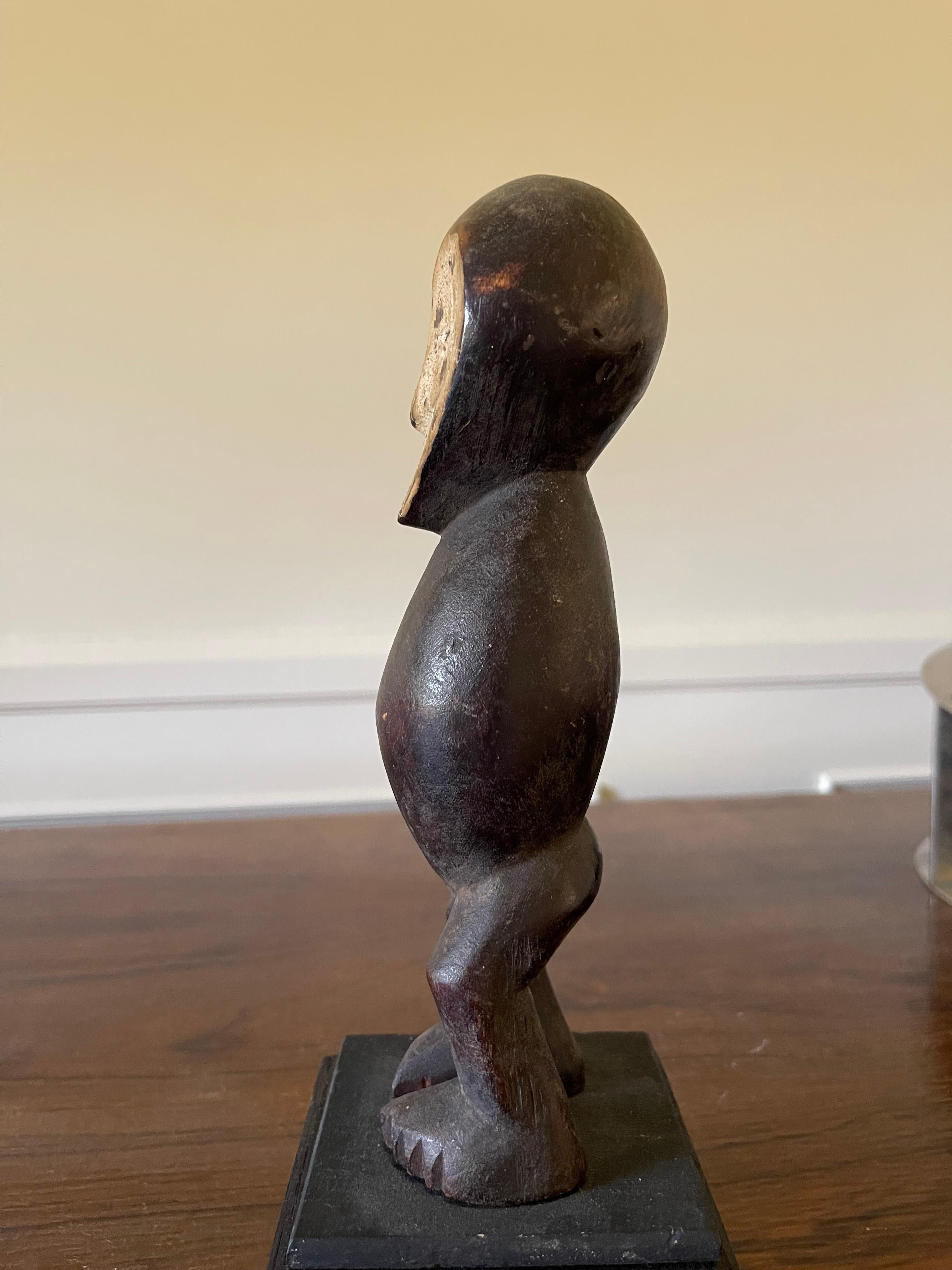 La patina liscia e scura di questa piccola statua di iniziazione maschile in legno, modellata con cura all'inizio del XX secolo dal popolo Lega della Repubblica Democratica del Congo, riflette la bellezza fisica e morale a cui aspirano gli iniziati.