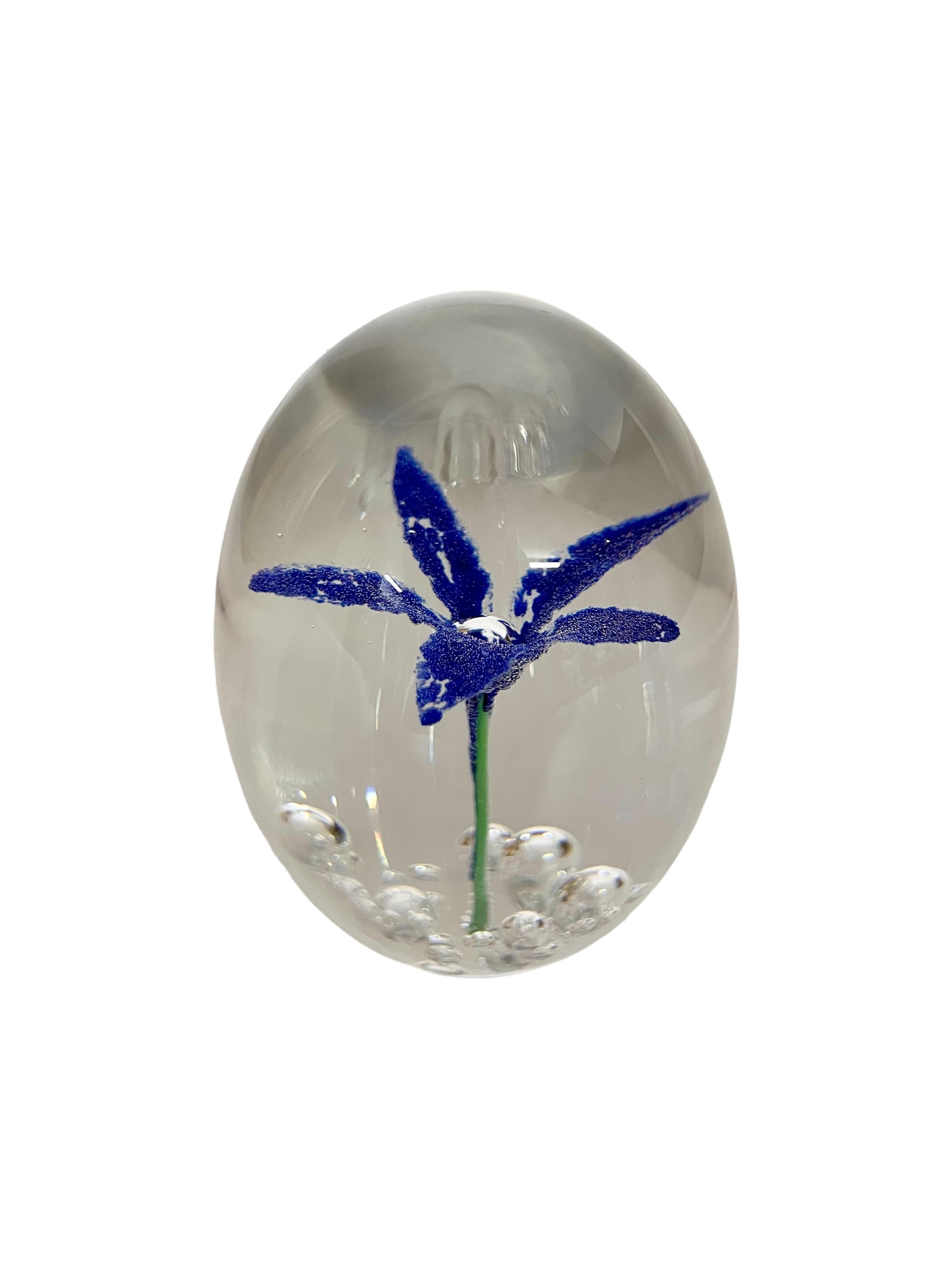 This stunning egg-shaped crystal paperweight is made by the legendary French glassmaker 'Daum', and features an incredibly intricate five-petalled violet-blue flower at its centre. Known as a 'sulphide' paperweight, this technique of encasing cast