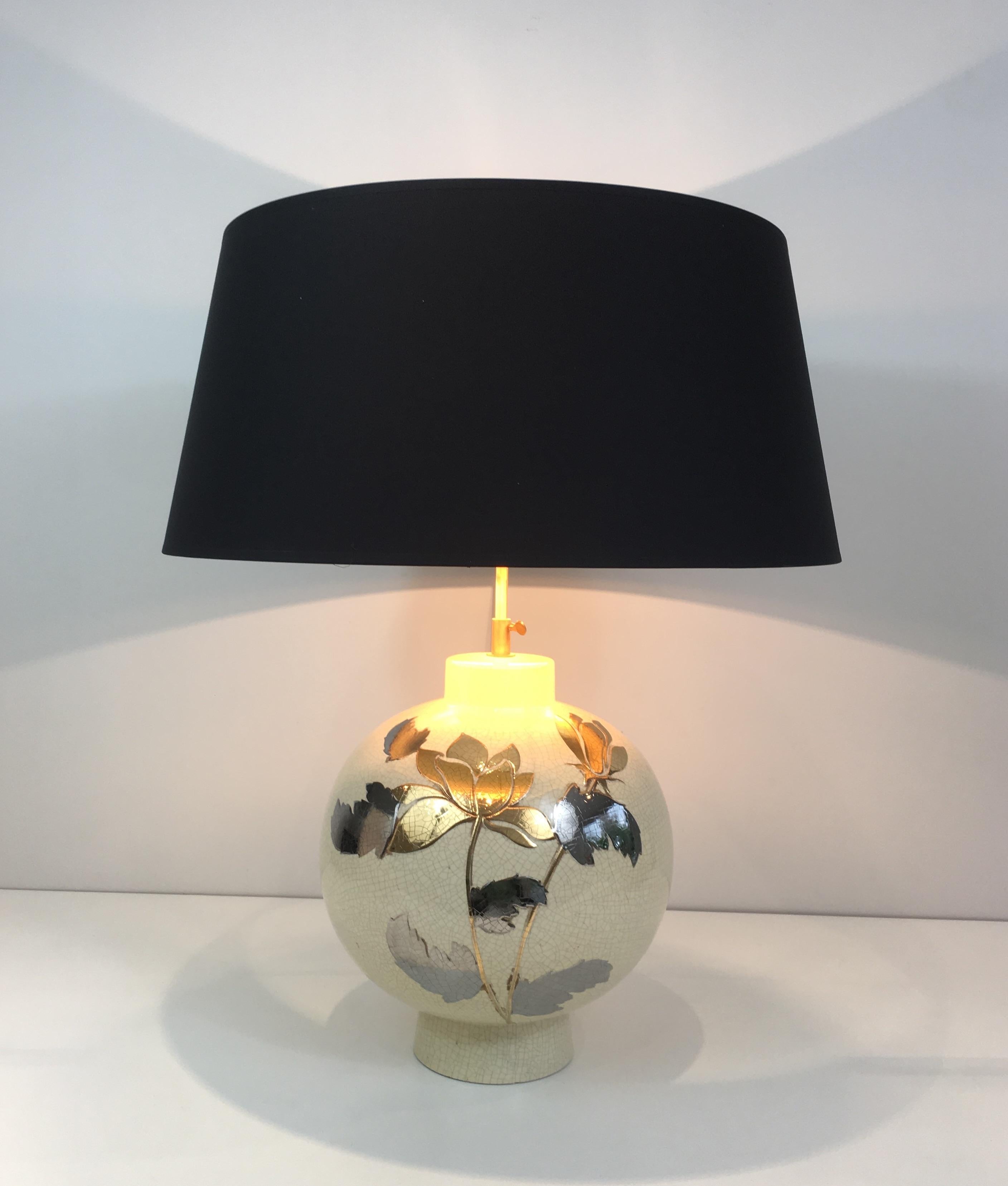 This table lamp is made of a cracked ceramic with a silver and gold flower decoration on the front. This is a French work, signed by L Drummer, circa 1970.