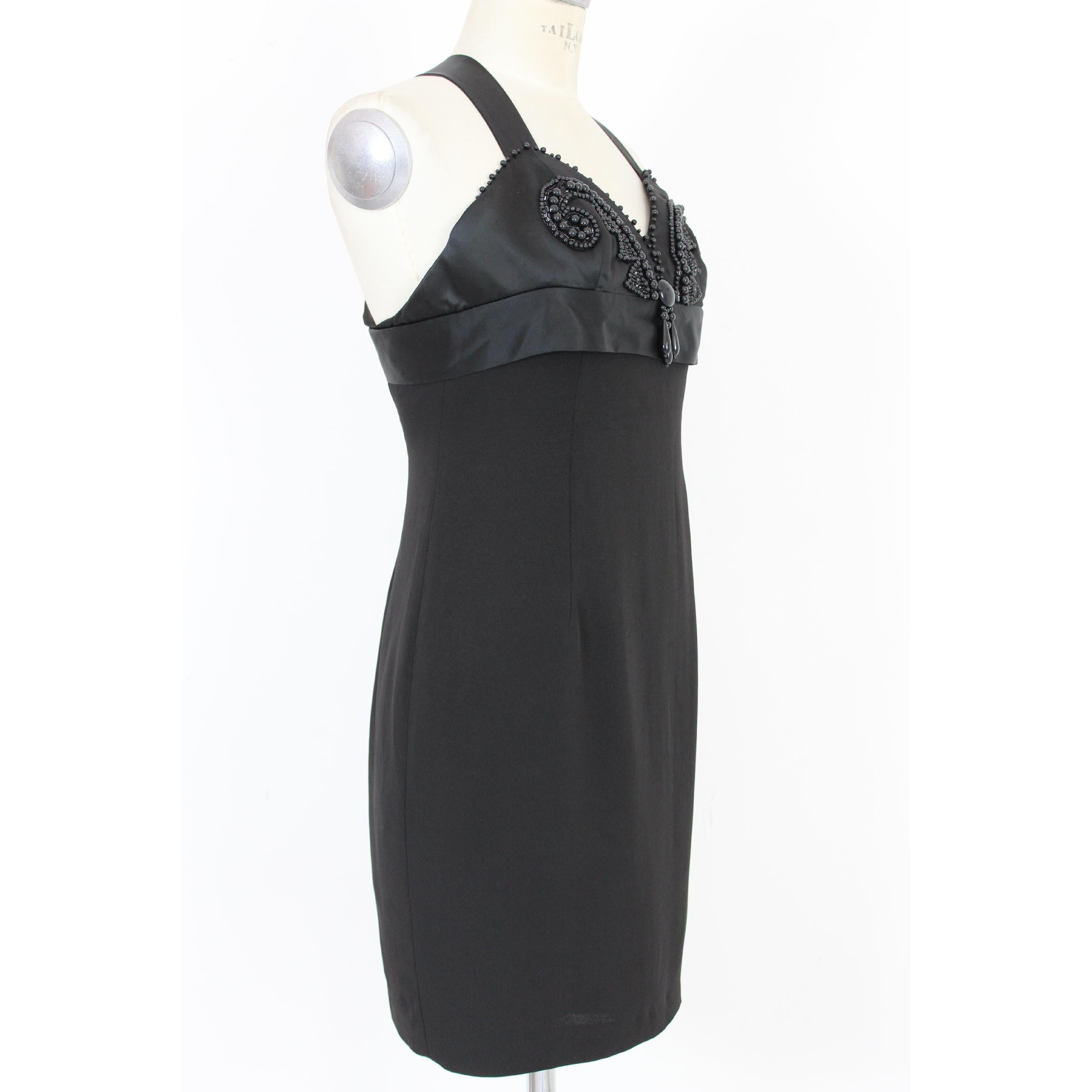 Byblos women's vintage dress 80s. Black, 50% acetate 50% viscose. Elegant dress, short model, on the chest details in tone-on-tone semi-precious sequins, crossed straps on the back in satin, internally lined. The dress is a size 42. Made in Italy.