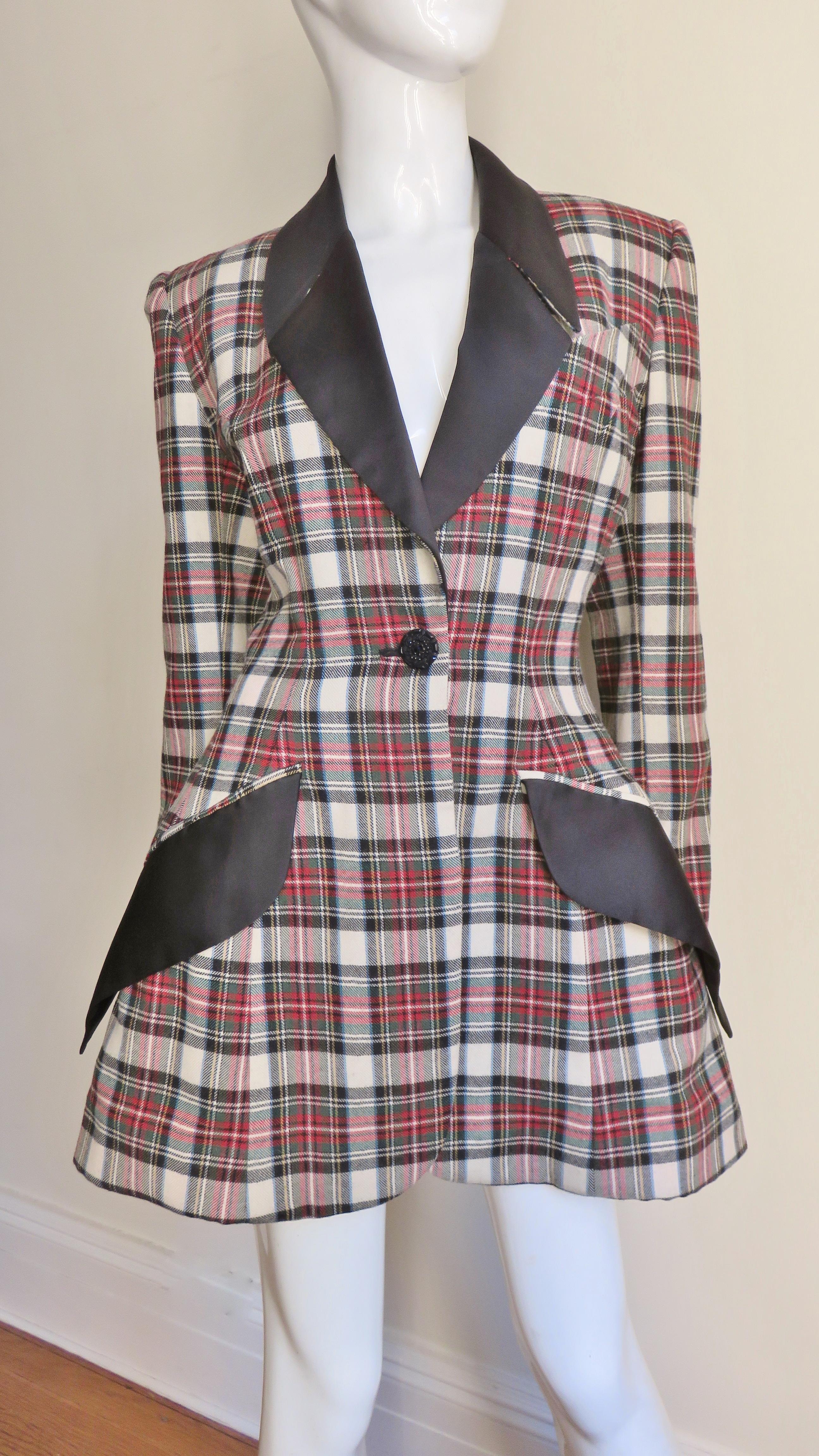 A fabulous wool and silk jacket from Byron Lars in an off white, red, black and green plaid.  The jacket has a lapel collar and angled hip flap pockets all in black silk.  It is fitted at the waist and flares to the hem with the fullness created