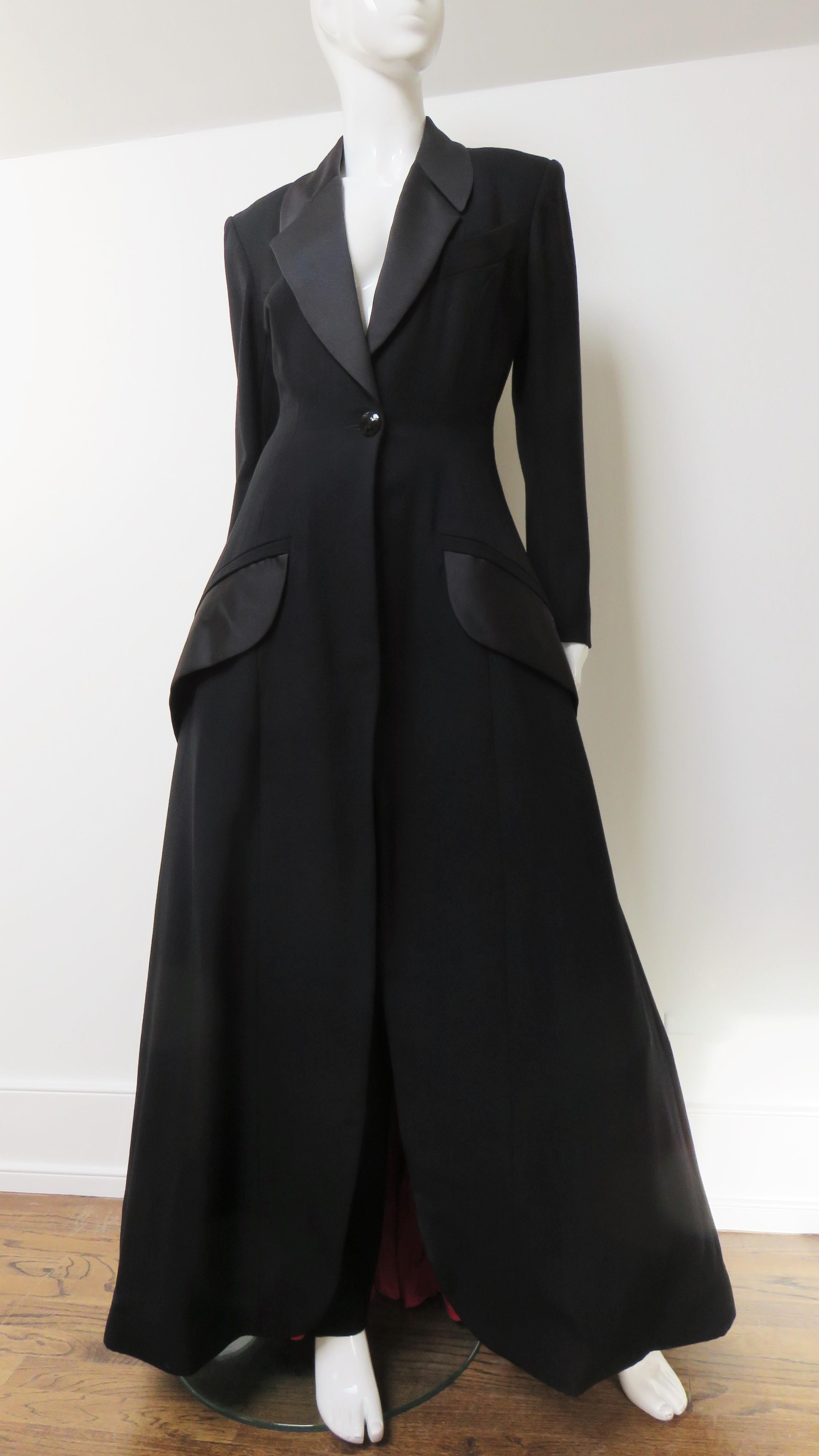 An incredible black wool and silk pant and floor length jacket set from the early couture collection of Byron Lars. The long  jacket has a black silk lapel collar, angled front flap pockets, and shoulder padding. It closes with a large black glass