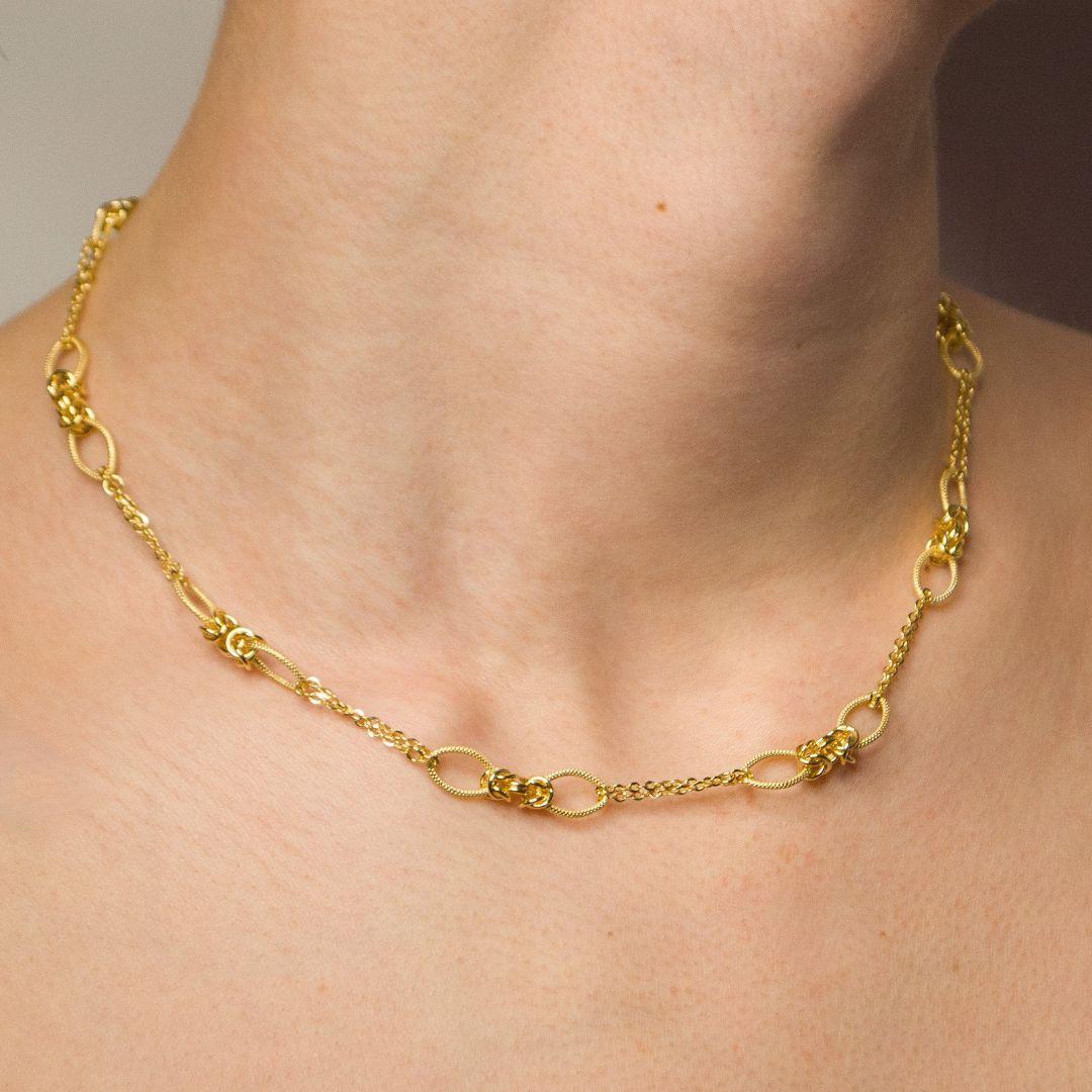 Elevate your everyday elegance with this 18k yellow gold Chain Necklace, featuring intricately crafted Byzantine-style charms. The textured oval links are interwoven with detailed knot motifs, creating a striking contrast of boldness and