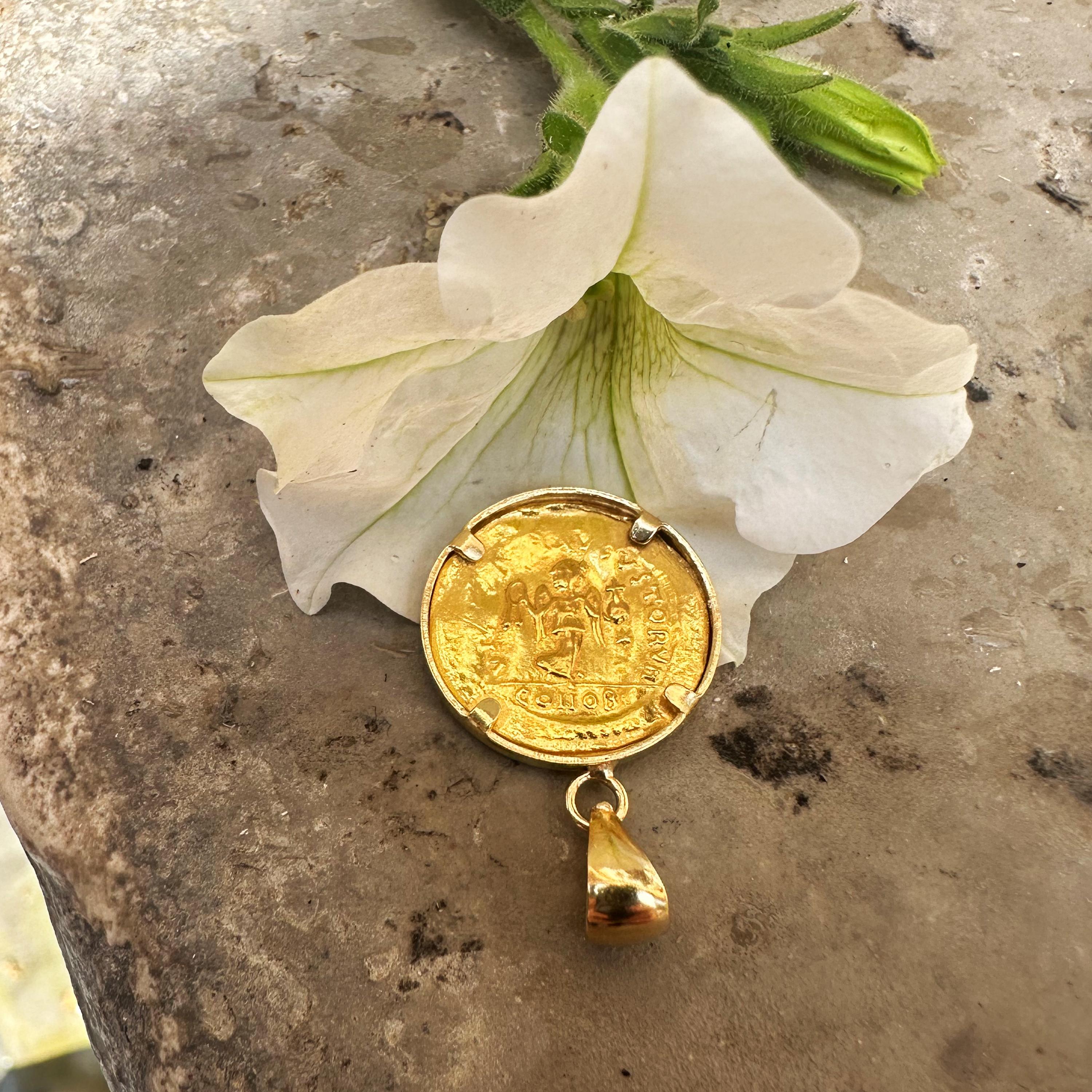 Cet exquis pendentif en or 18 carats renferme une pièce de monnaie byzantine en or 24 carats (Tremissis) du 6e siècle ADS représentant l'empereur Justinien Ier. Au verso, on peut voir la Victoire tenant le globus et la couronne ; l'étoile à