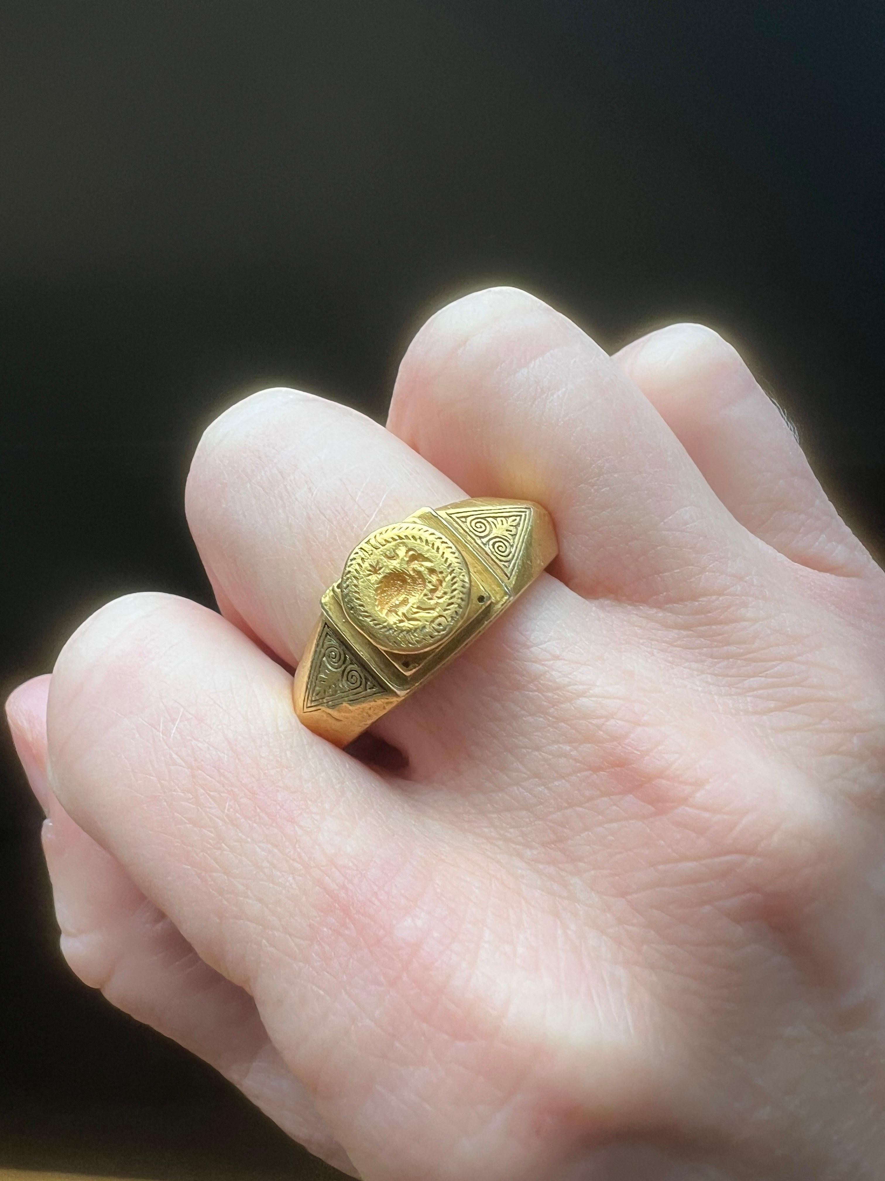 A remarkable and finely crafted Byzantine 22kt gold ring featuring a raised circular bezel with an intaglio engraving of a bird and a lizard or salamander—creatures rich in early Christian symbolism. The central boss is set atop stepped plinths,