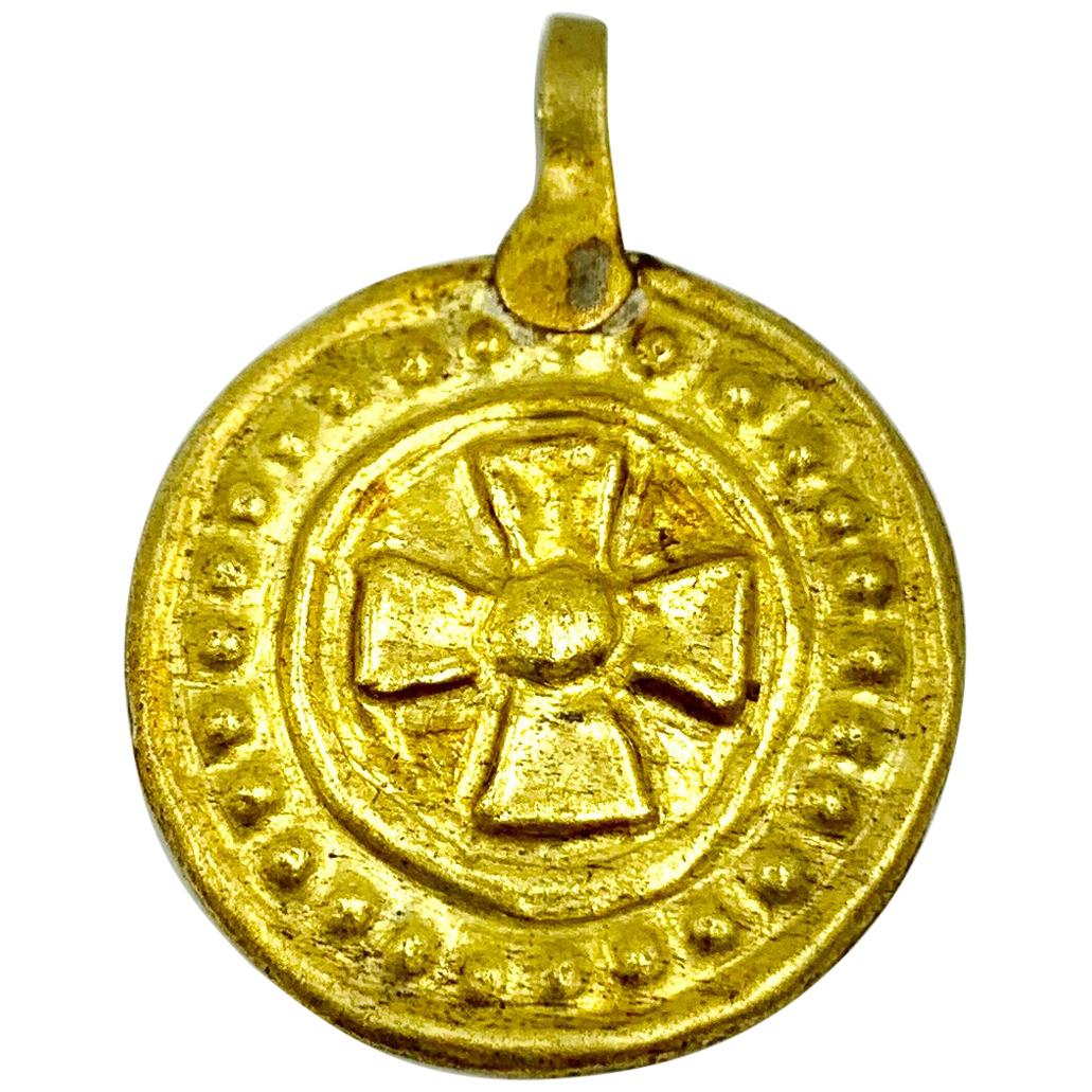 The circular gold pendant medallion embossed with a pectoral cross of Saint Cuthbert in relief, with a beaded border frame. This type of cross is also known as Thor's Cross for its connection to Cuthbert who was a Celtic Christian. Beautiful patina