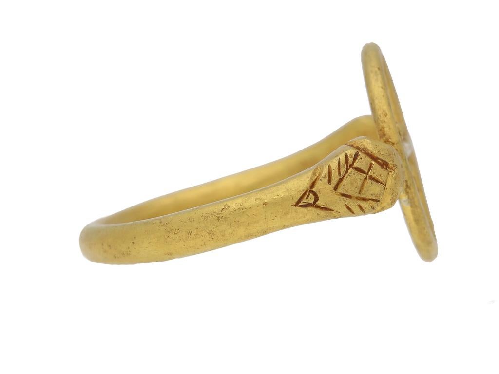 Byzantinischer Goldring mit Kreuz. Ein Gelbgoldring mit einer kreisförmigen durchbrochenen Plakette in der Mitte mit einem Kreuzmotiv, das mit Goldgranulat verziert ist, flankiert von zoomorphen Endstücken, die fein mit stilisierten Schuppen