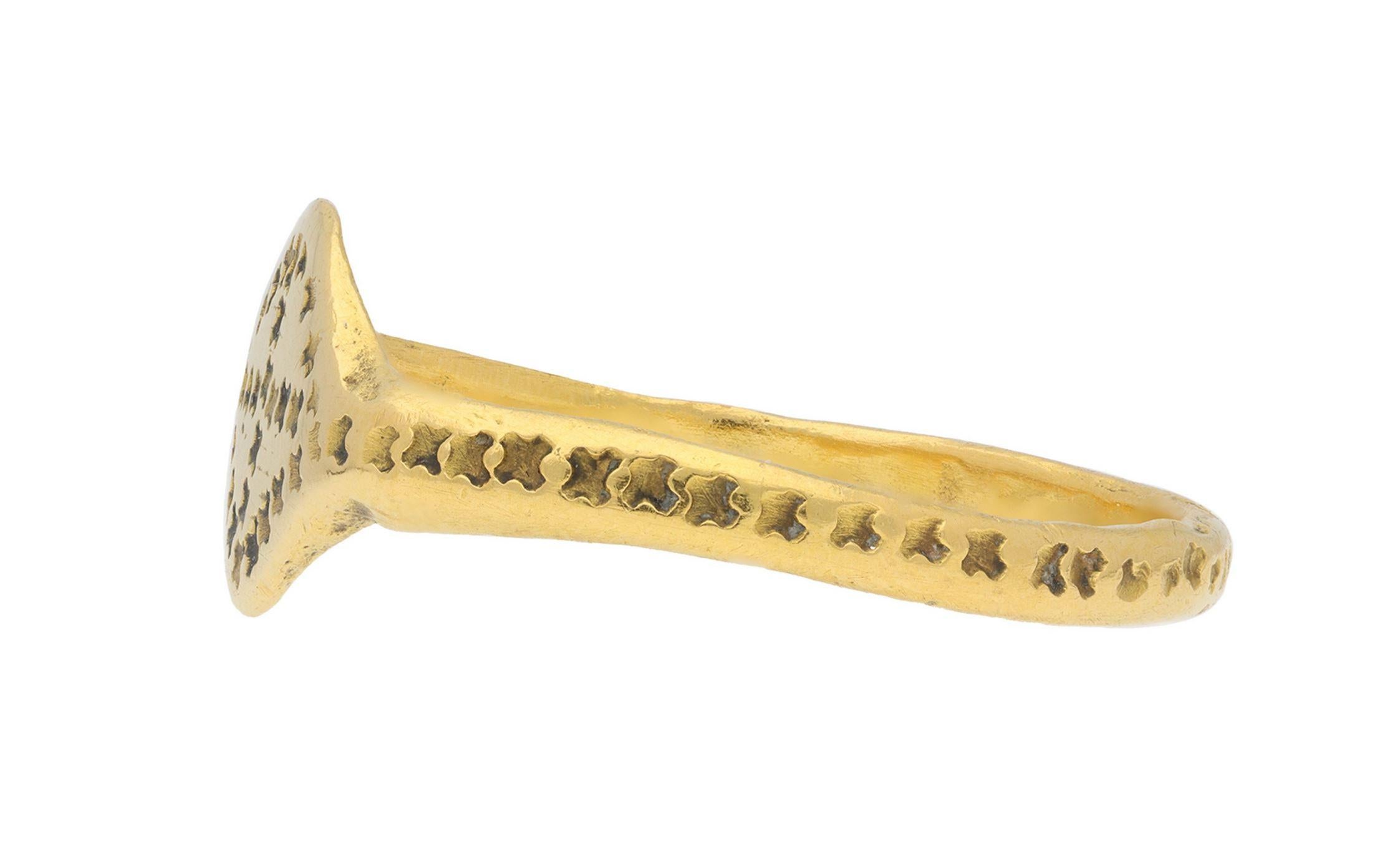 Byzantine gold stamped ring. The central flat lozenge form plaque stamped with a repeating X shape punch with traces of niello, flanked by conforming shoulders which smoothly lead through to a solid D-shape shank, the punchmarks following the full