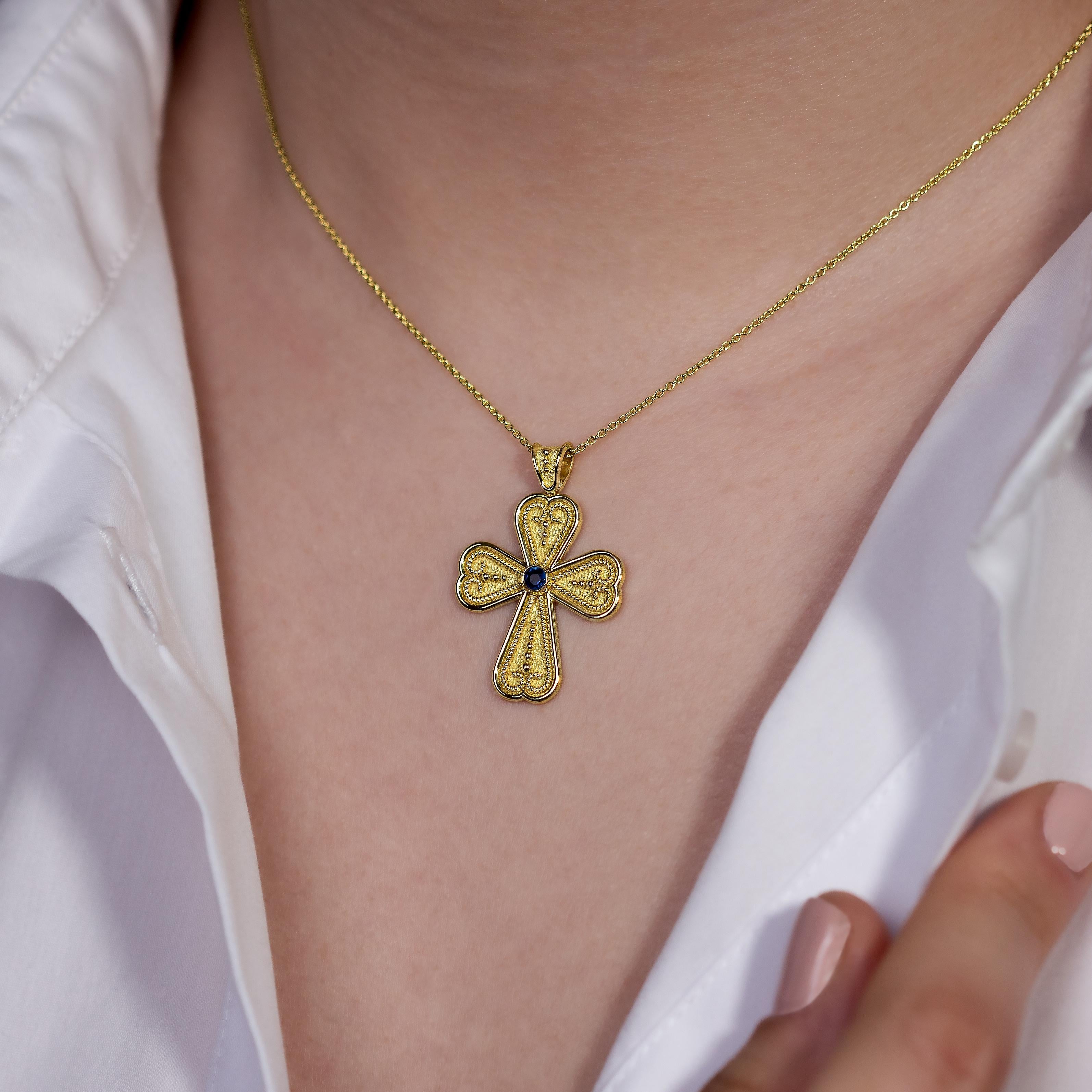 Schmücken Sie Ihr Dekolleté mit der bezaubernden Schönheit eines byzantinischen Herzkreuz-Anhängers, in dessen Zentrum ein einzelner, strahlender Saphir steht - ein geschätztes Symbol für dauerhafte Liebe und komplexe Kunstfertigkeit, die die Zeit