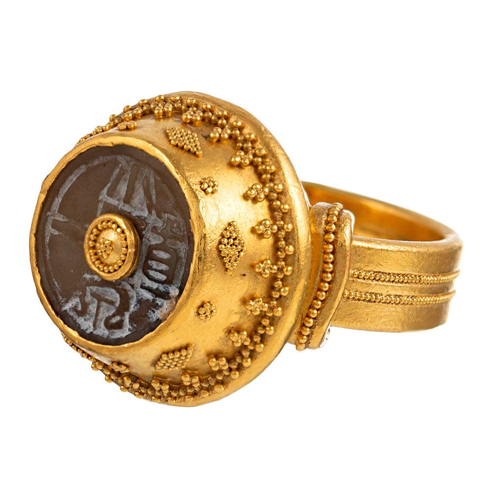 Created in 22 karat yellow gold, this glowing handmade ring is a work of wearable art, signed by Luna Felix. Granules of gold and a carved agate centerpiece resembling an ancient coin create a conversation-worthy adornment for your hand that can be