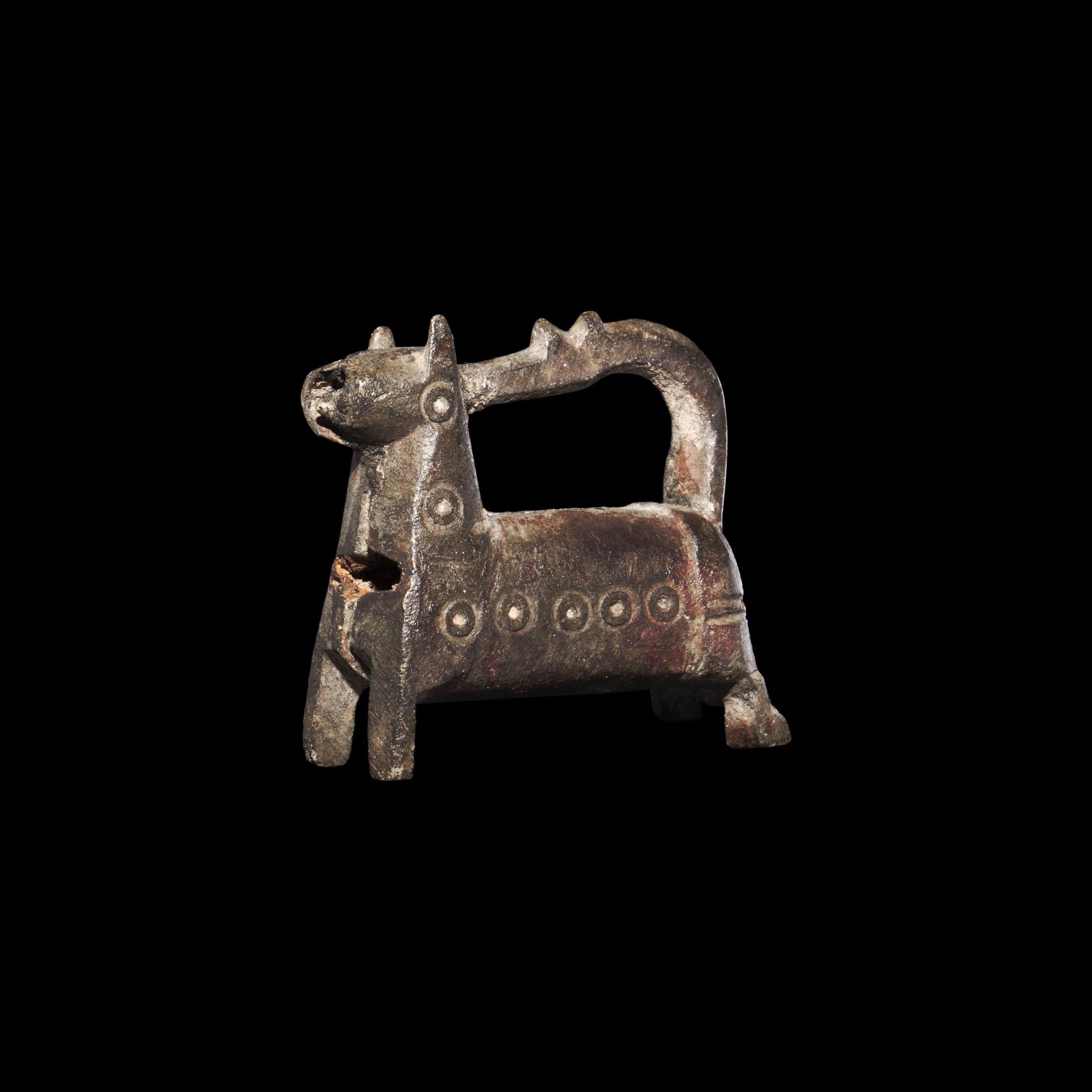 A bronze barrel-lock formed as a standing horse with curved legs, ring-and-dot motifs to the body, the recurved tail forming the hasp. 

33.2 grams, 36mm (1 1/2