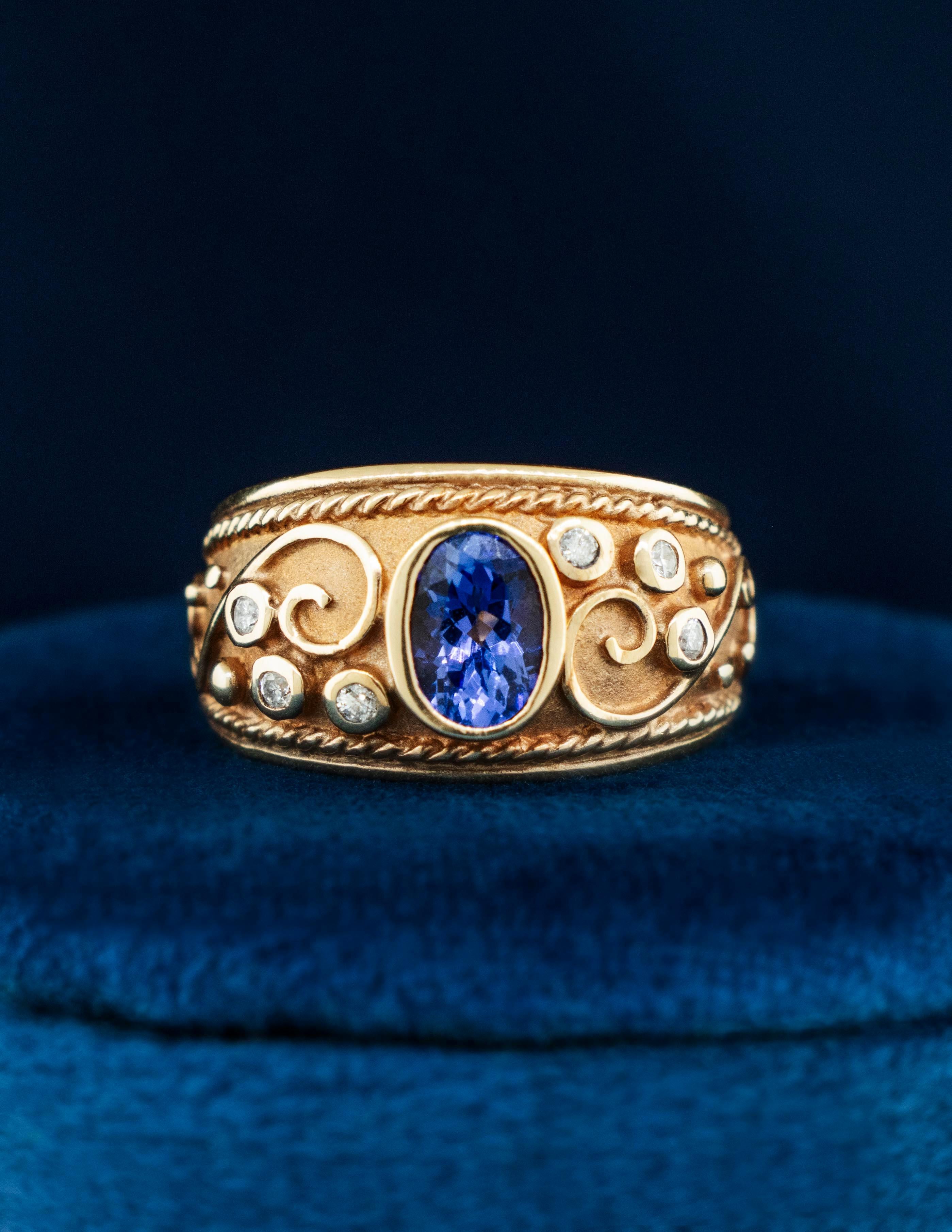 Anillo bizantino de oro amarillo de 14 quilates con una brillante piedra central ovalada de tanzanita flanqueada por diamantes redondos brillantes. El estilo bizantino se originó en la antigua Grecia y sigue siendo uno de los más buscados hoy en