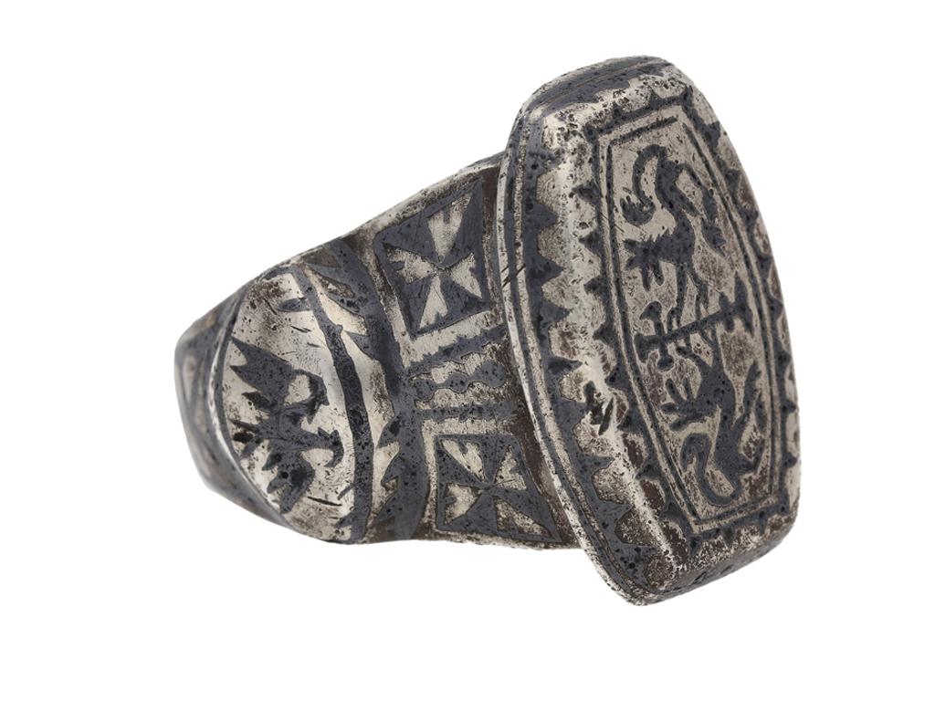 Byzantine silver and niello ring. A heavy solid ring, fitted to centre with a raised rounded oblong bezel featuring two niello opposed advancing lions grasping a processional cross, bordered by undulating pattern, flanked either side by broad