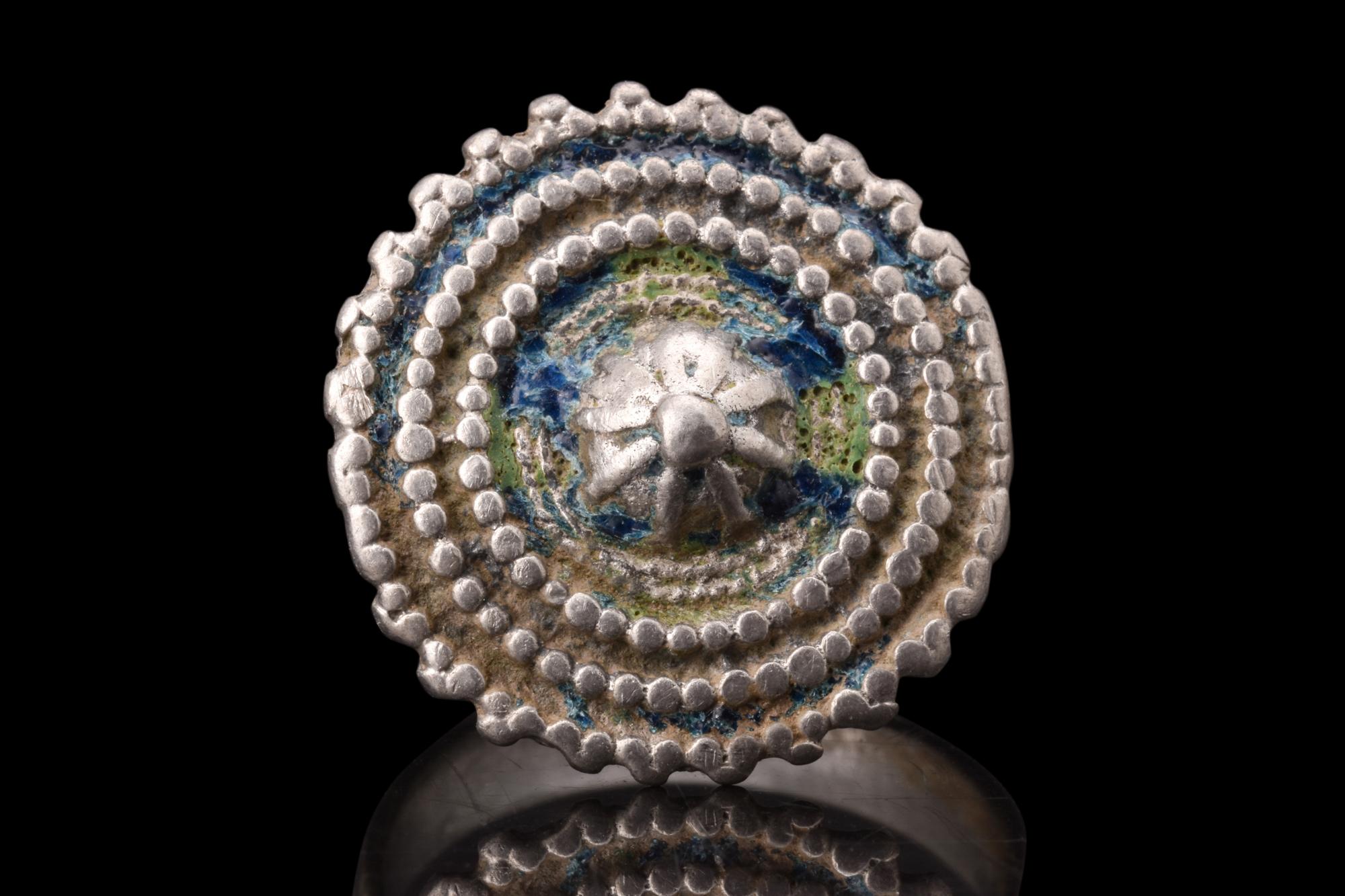 A silver Byzantine ring, distinguished by its large, granulated shield bezel, which reflects the artistic prowess and cultural significance of the Byzantine Empire. The ring possesses a round hoop with a flat-section shank. Its applied bezel