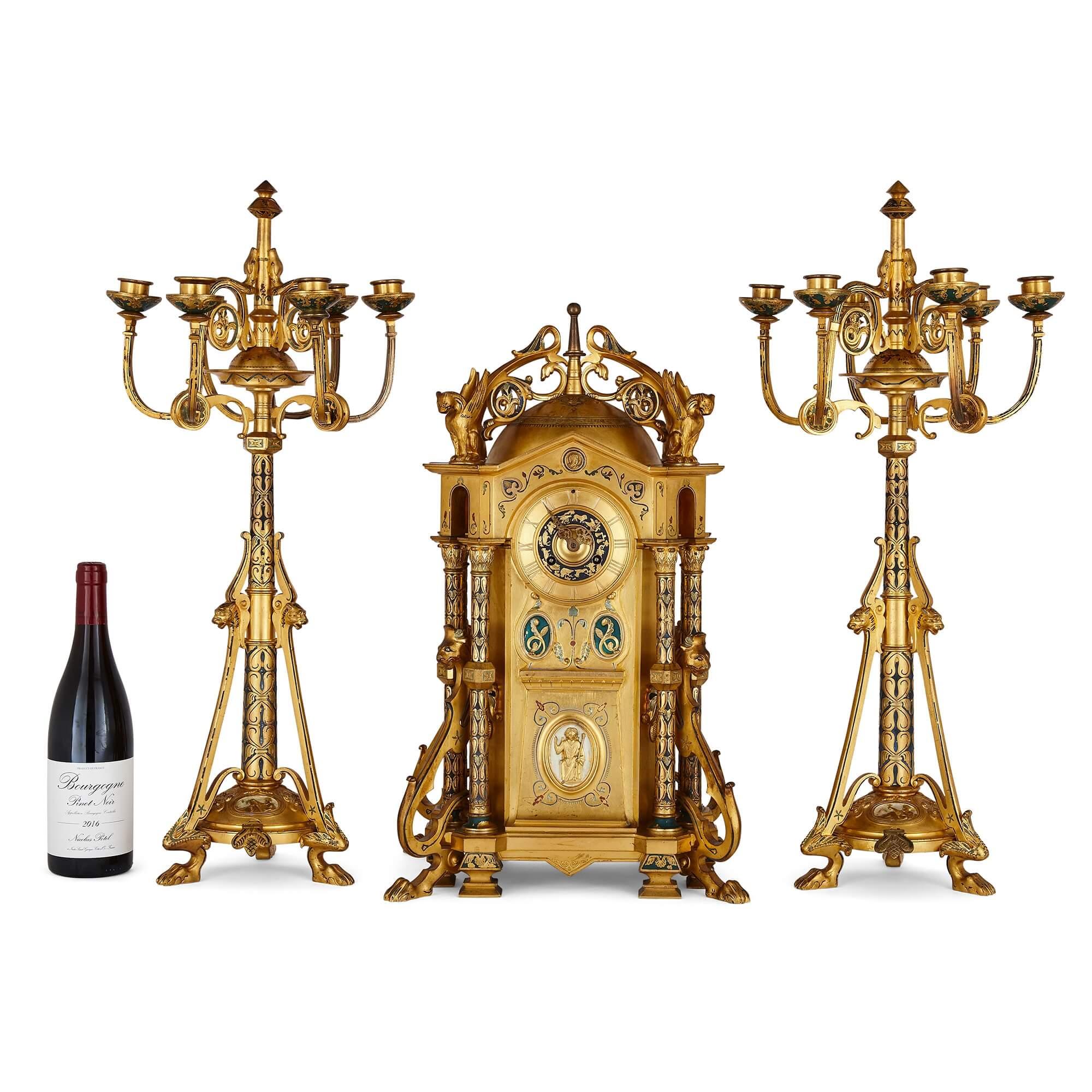 Byzantine style gilt bronze and champlevé enamel clock garniture by Raingo Frères
French, late 19th century
Measures: Clock: Height 55cm, width 34cm, depth 25cm
Candelabra: Height 67cm, width 31cm, depth 28cm

The present clock set is by Raingo