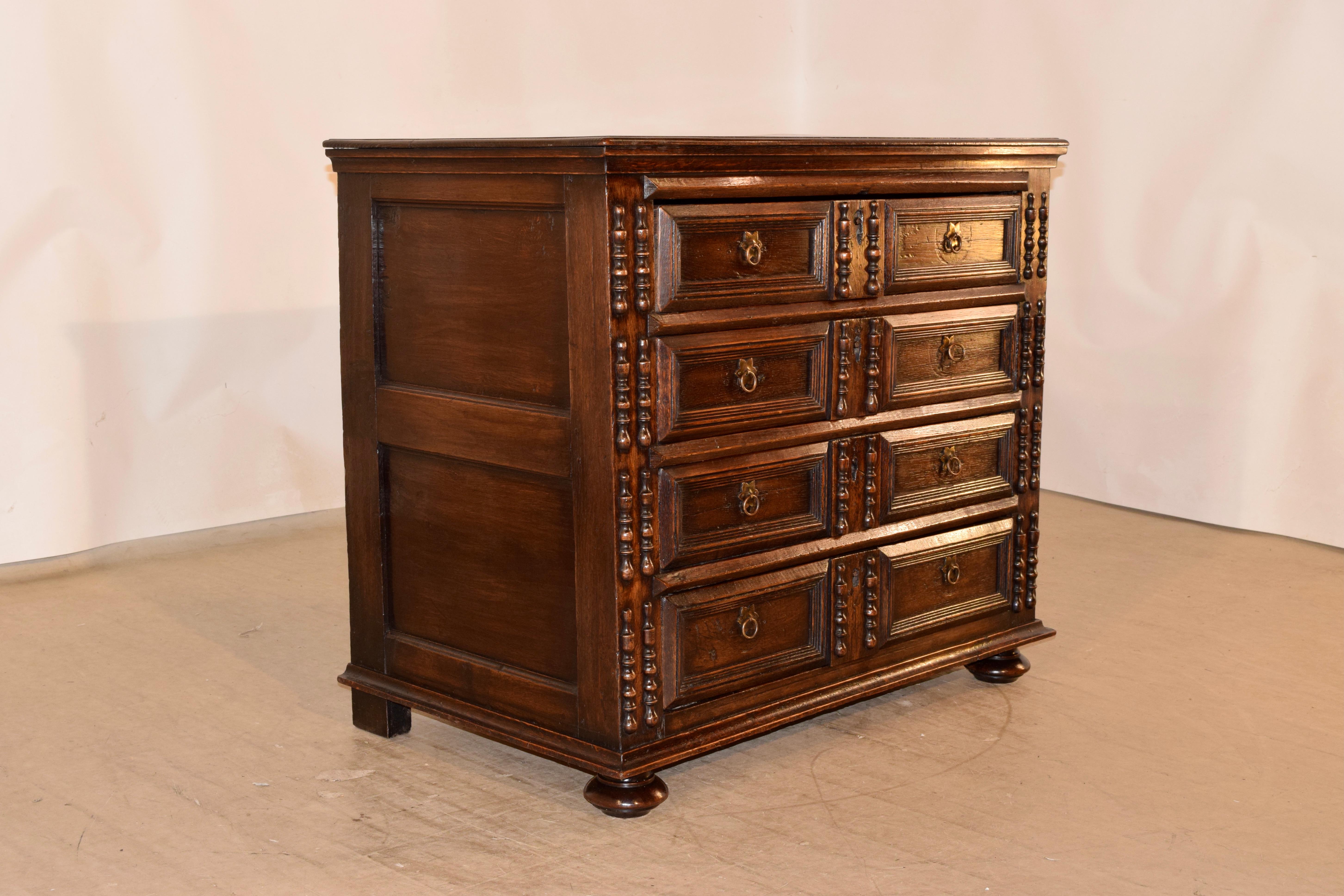 Late 17th - early 18th century oak chest of drawers from England made from oak. The top has a nicely beveled edge, following down to hand paneled sides and four raised paneled drawers in the front, flanked with pairs of applied turnings. The case