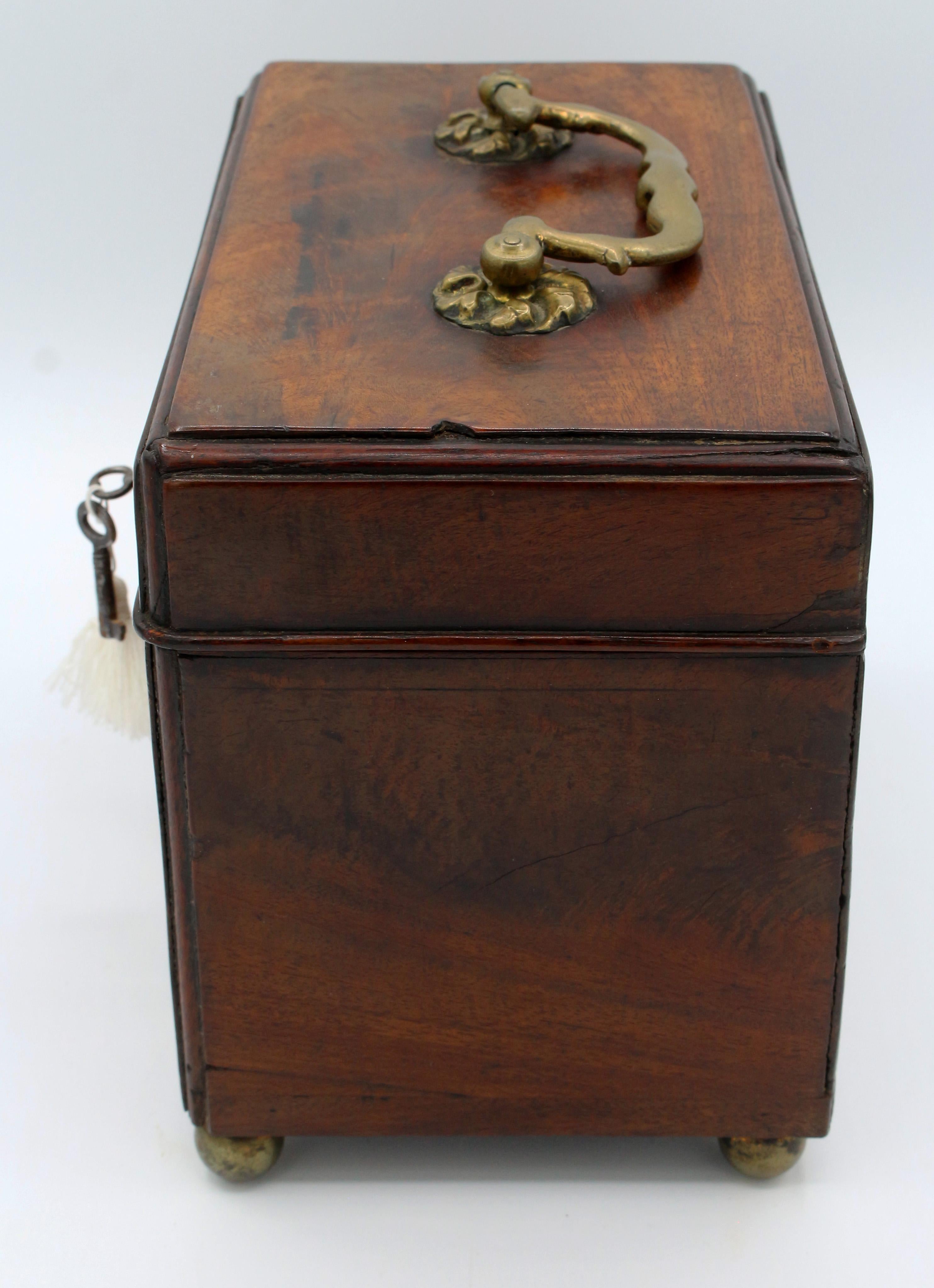 George III tea caddy, circa 1765, English. Raised on later Regency brass ball feet. Mahogany on oak. Working lock. Alterations circa 1780 to the interior adding a spoon compartment and the escutcheon. Minor bumps & small veneer patch commensurate