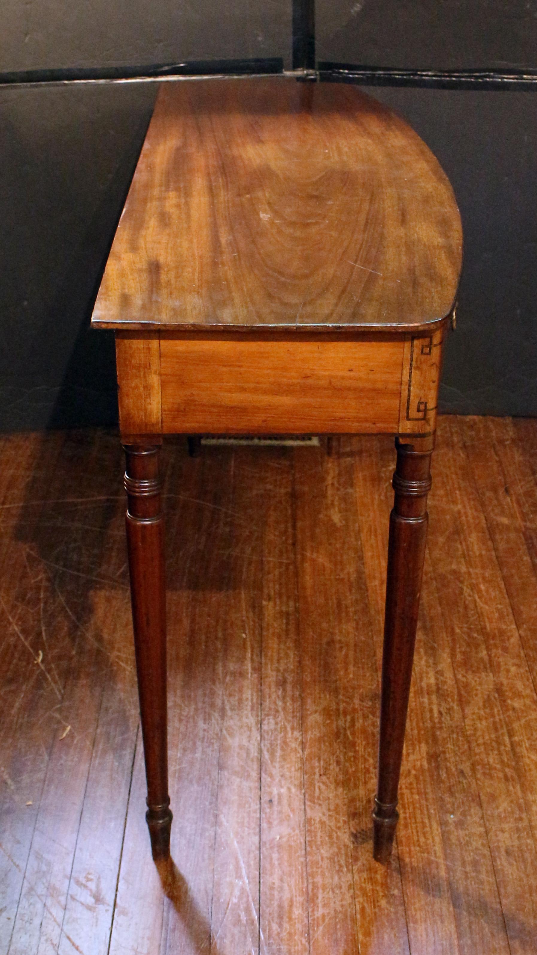 Circa 1800-1810 early Regency period 3-drawer console table or server, English. An elegant bowfront form raised on Sheraton design long, turned, tapered, ring-turned legs. Ebony inlays, particularly fashionable about 1805 with Admiral Nelson's death