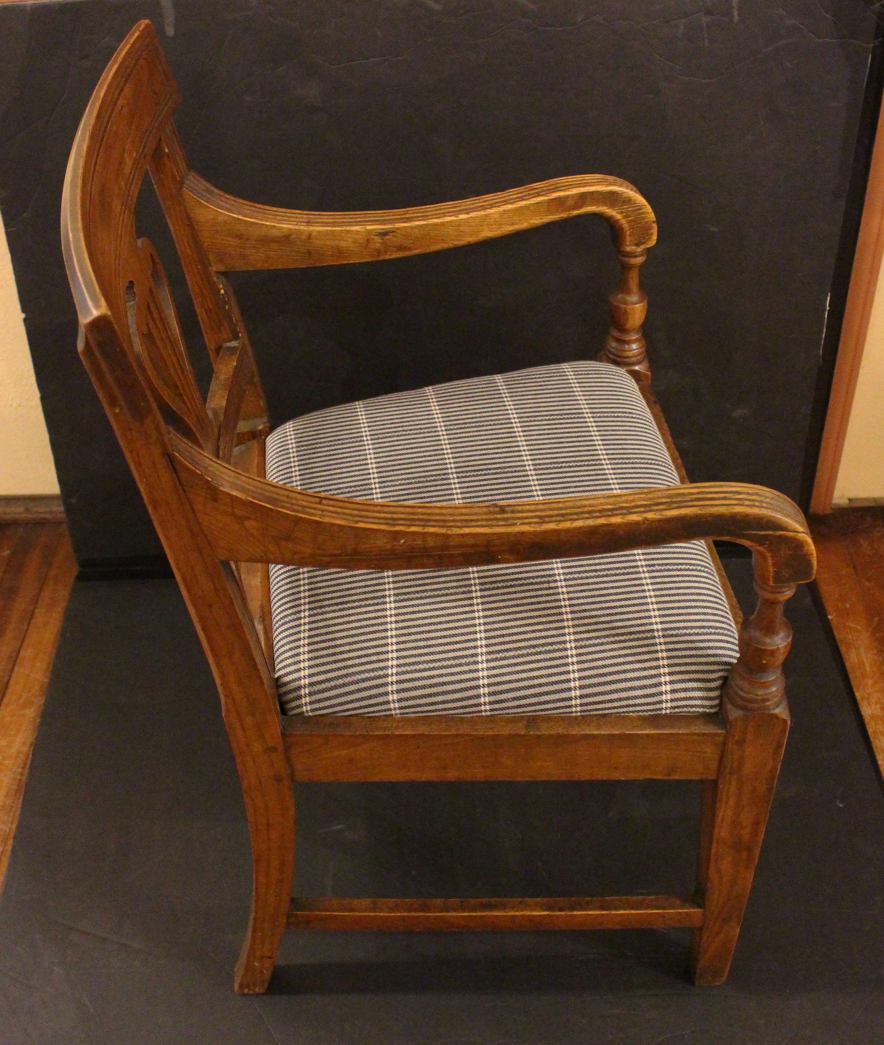 Sillón de época de la Regencia inglesa, circa 1800-1820. En madera de fresno bien labrada y de color cálido, el primo campestre de los de caoba de la ciudad. Levantada sobre atrevidas patas cuadradas y cónicas con camillas. Brazos acanalados