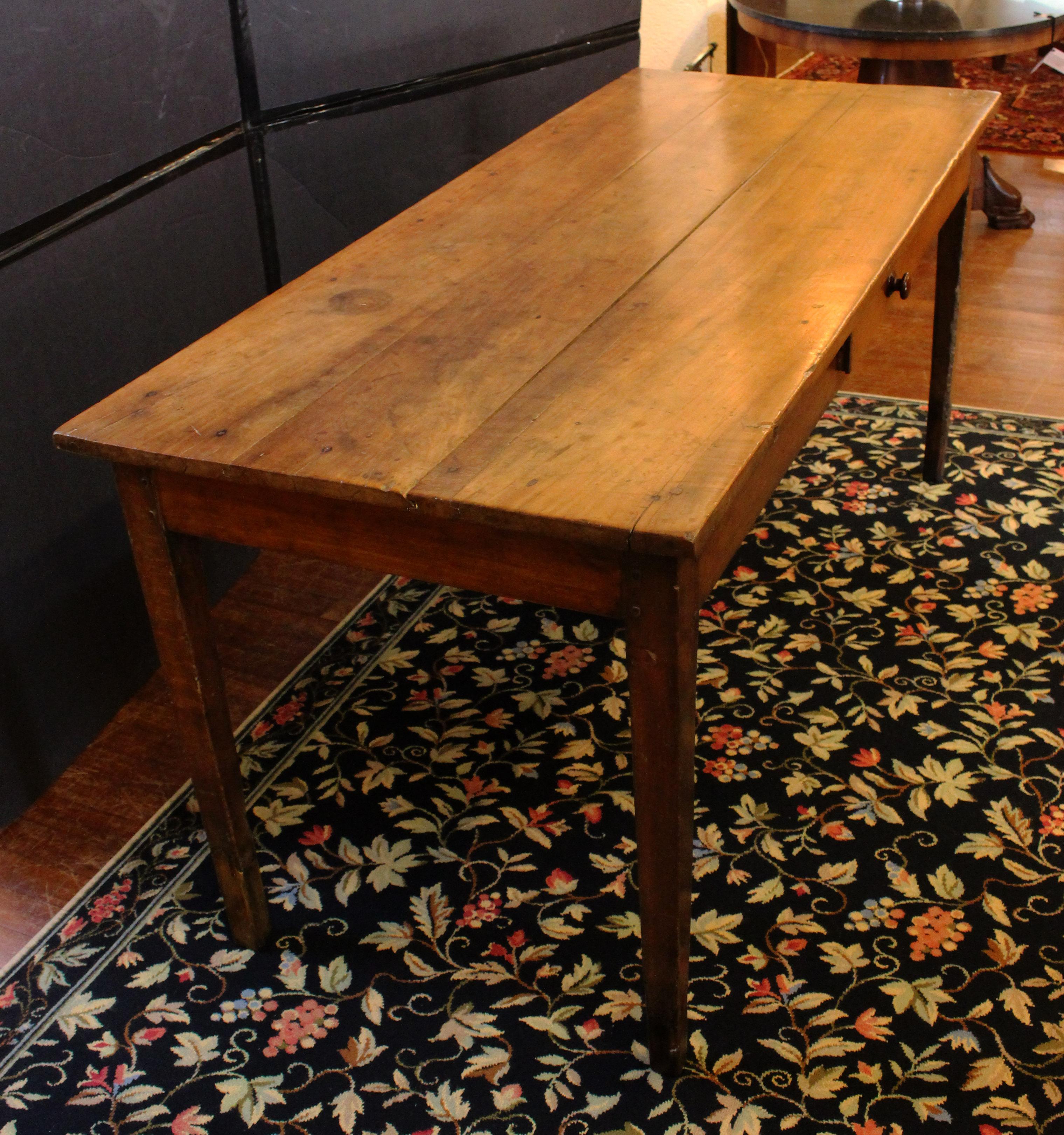 Country French farm table of fruitwood, circa 1800. Raised on square, tapered legs. Divided apron drawer with treen pull. Two-board top. Tipped feet, typical of these tables which were on stone floors for centuries. Family provenance: purchased in