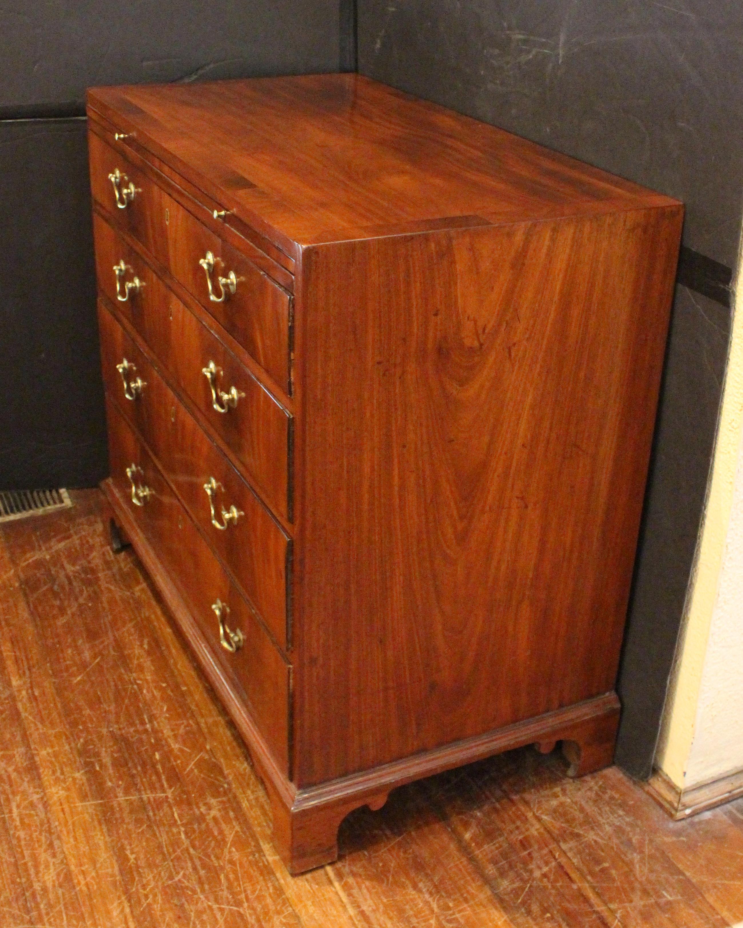 Cassettiera georgiana da scapolo con slitta, inglese. Mogano ben figurato; cassa in mogano massiccio; legno secondario di pino per i cassetti. Ottimo l'uso di impiallacciature a fiamma sui frontali dei cassetti. Top a bande incrociate. Quattro