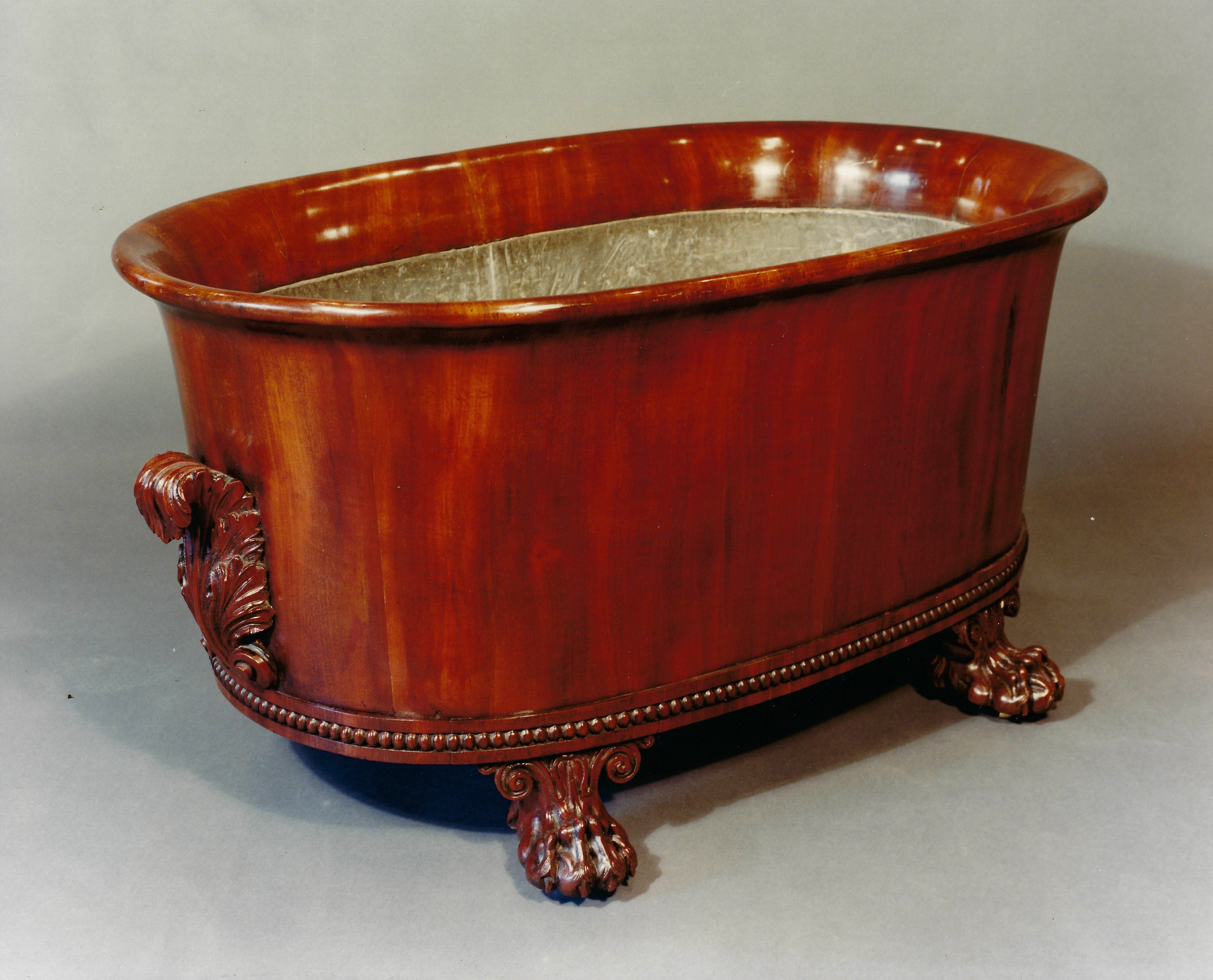 Regency period, circa 1815, grand scale oval wine cooler, English. Exceptional quality. Mahogany. Oval flared form accented by robust acanthus carved scrolled handles; beaded plinth; short double scrolled legs ending in finely detailed carved paw