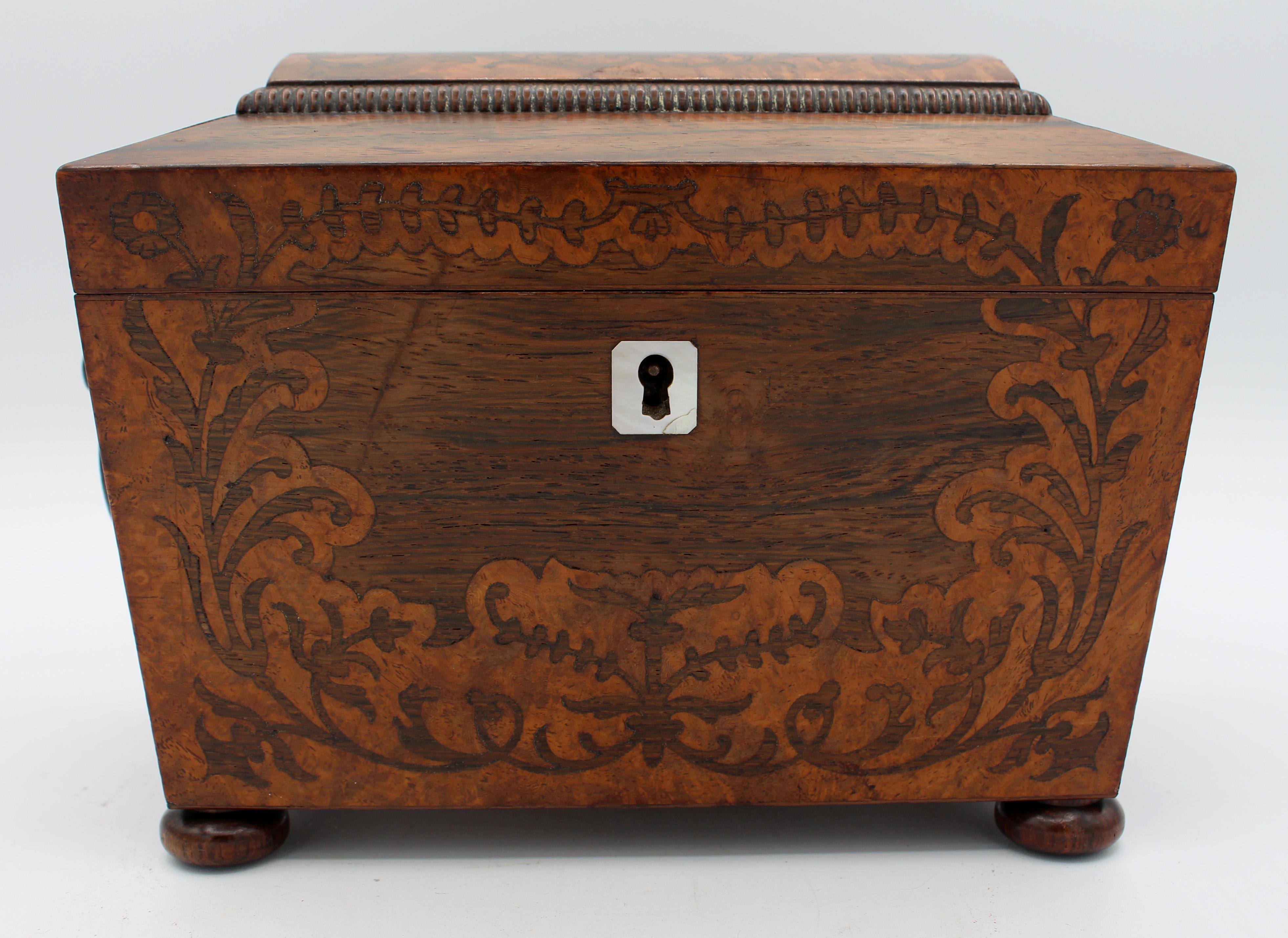 Vers 1820, boîte à thé en forme de sarcophage, anglais. Marqueterie de bois de rose et de ronce de thuya. Pieds de bouton. Le contraste entre les bois est visuellement excitant, plein de mouvement dans le grain et le dessin. Écusson en nacre.