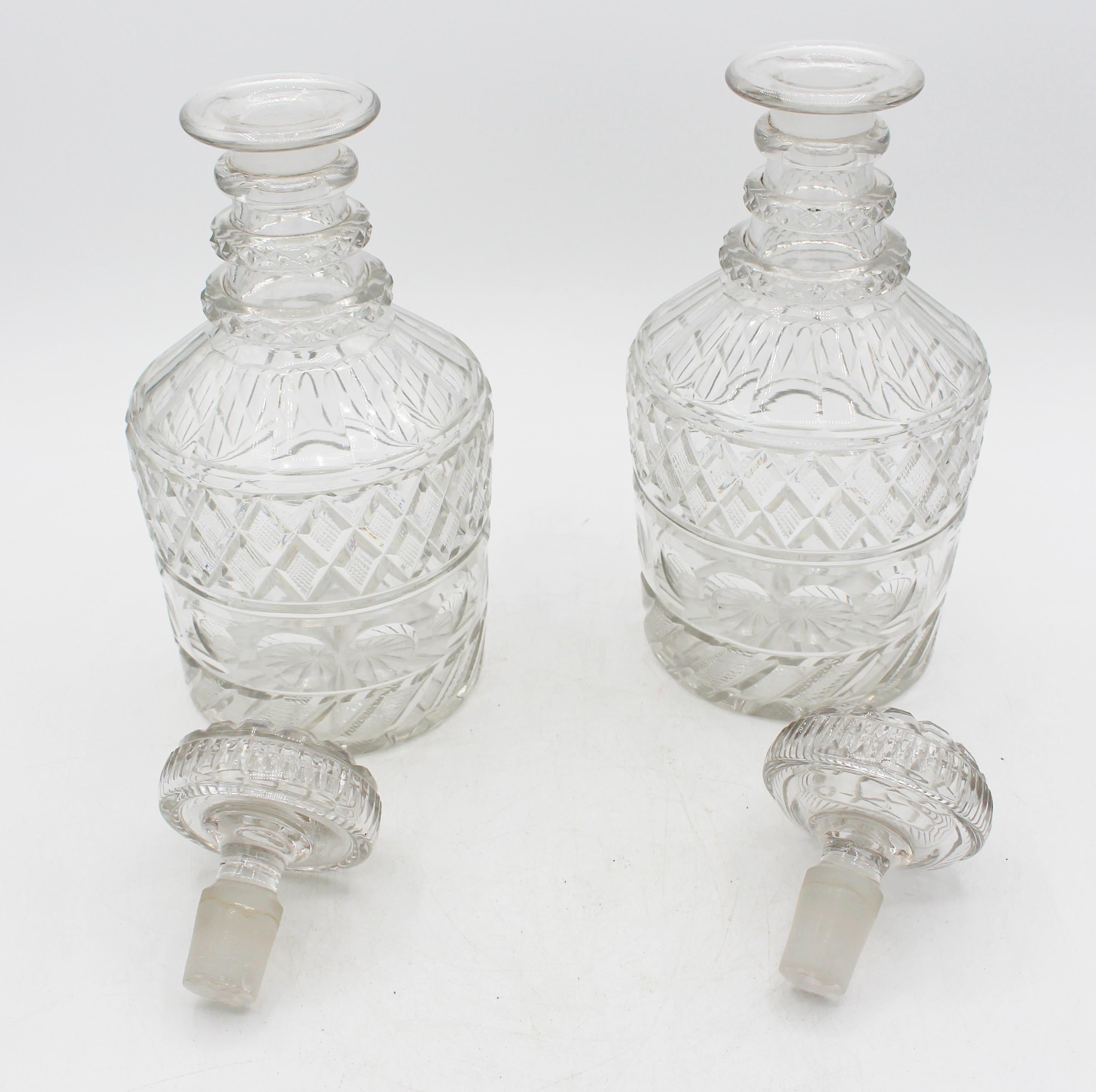 CIRCA 1820 Zwei georgische anglo-irische Dekanter aus geschliffenem Glas. Originalverschlüsse. Getäfelte Schultern über diamantgeschnittenem Band, das sich auf den Stöpseloberteilen wiederholt. Stopper endet mit Nibbles auf der einen und Chips auf