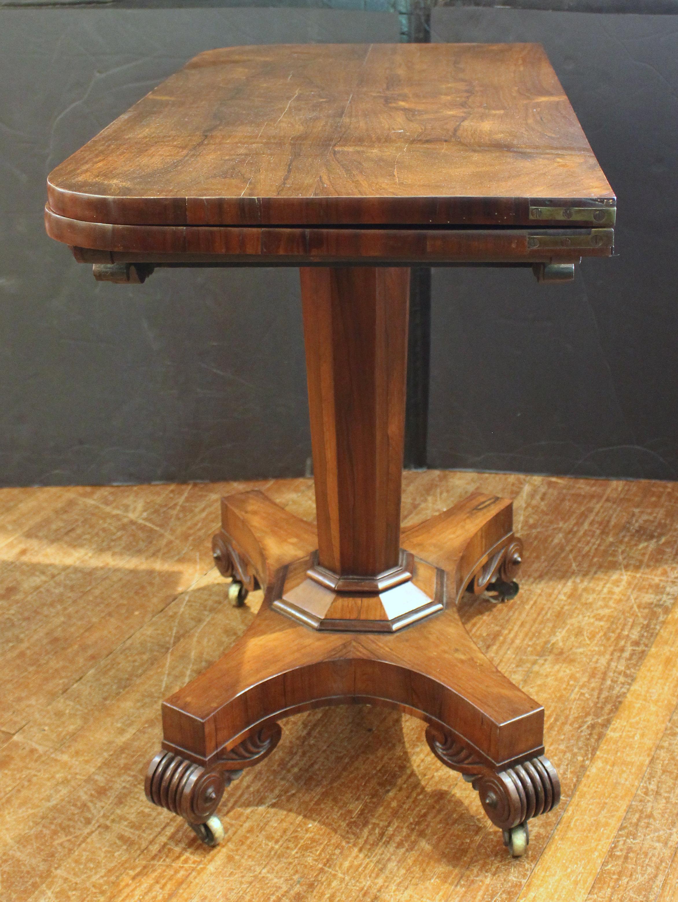 Table à jeux à plateau pivotant, vers 1820, anglais. Régence. La frise centrale du tablier est flanquée de sculptures en spirale et en acanthe. Le piédestal octogonal fuselé se prolonge par une base en abaque sur des pieds cannelés et