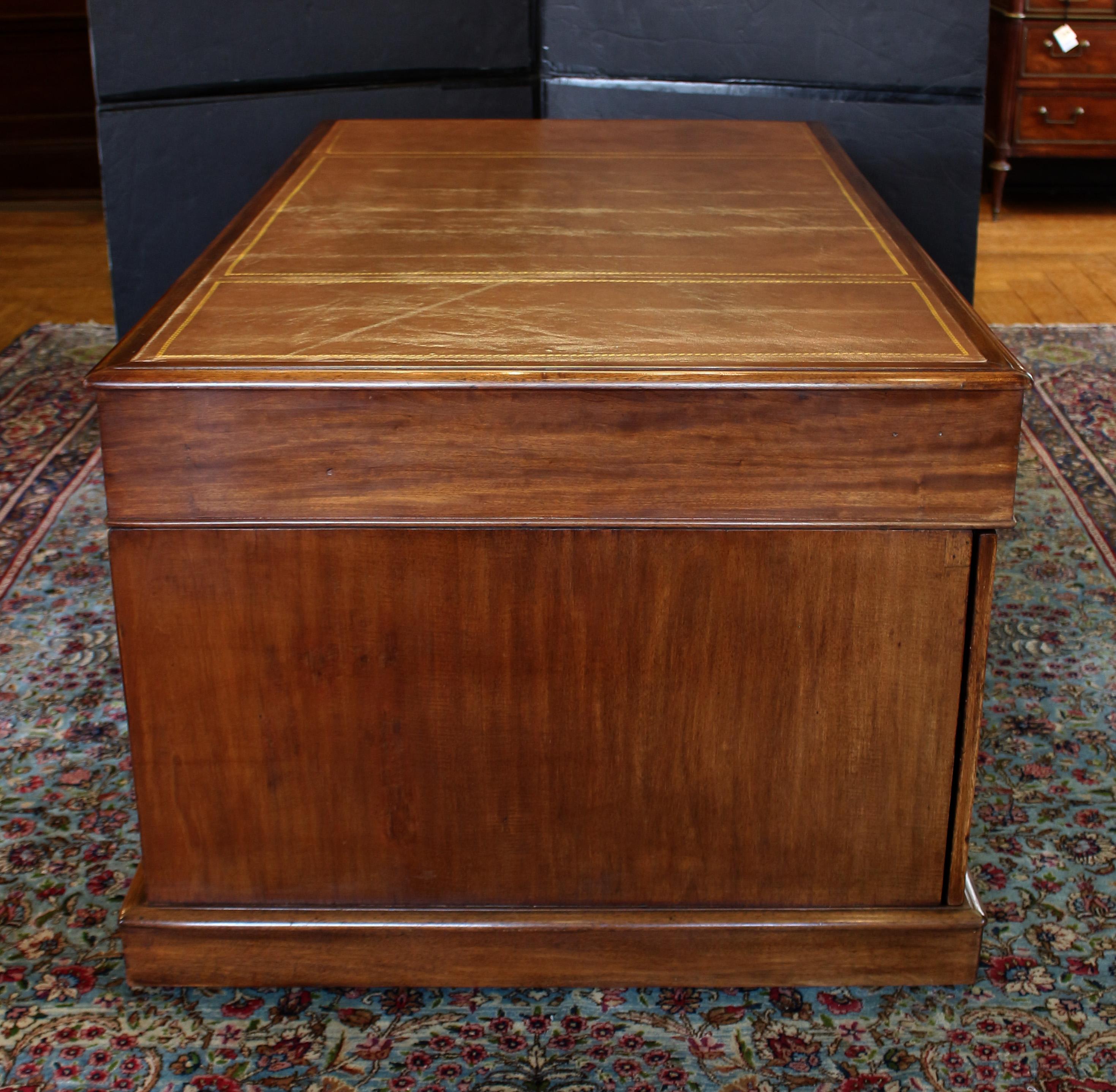 Circa 1830 Late Georgian Period English Partner's Desk. Handsome mahogany with leather writing surface (replaced leather, likely dating to the mid-20th century). Raised on plinth base (concealed casters), the center drawers wide but well
