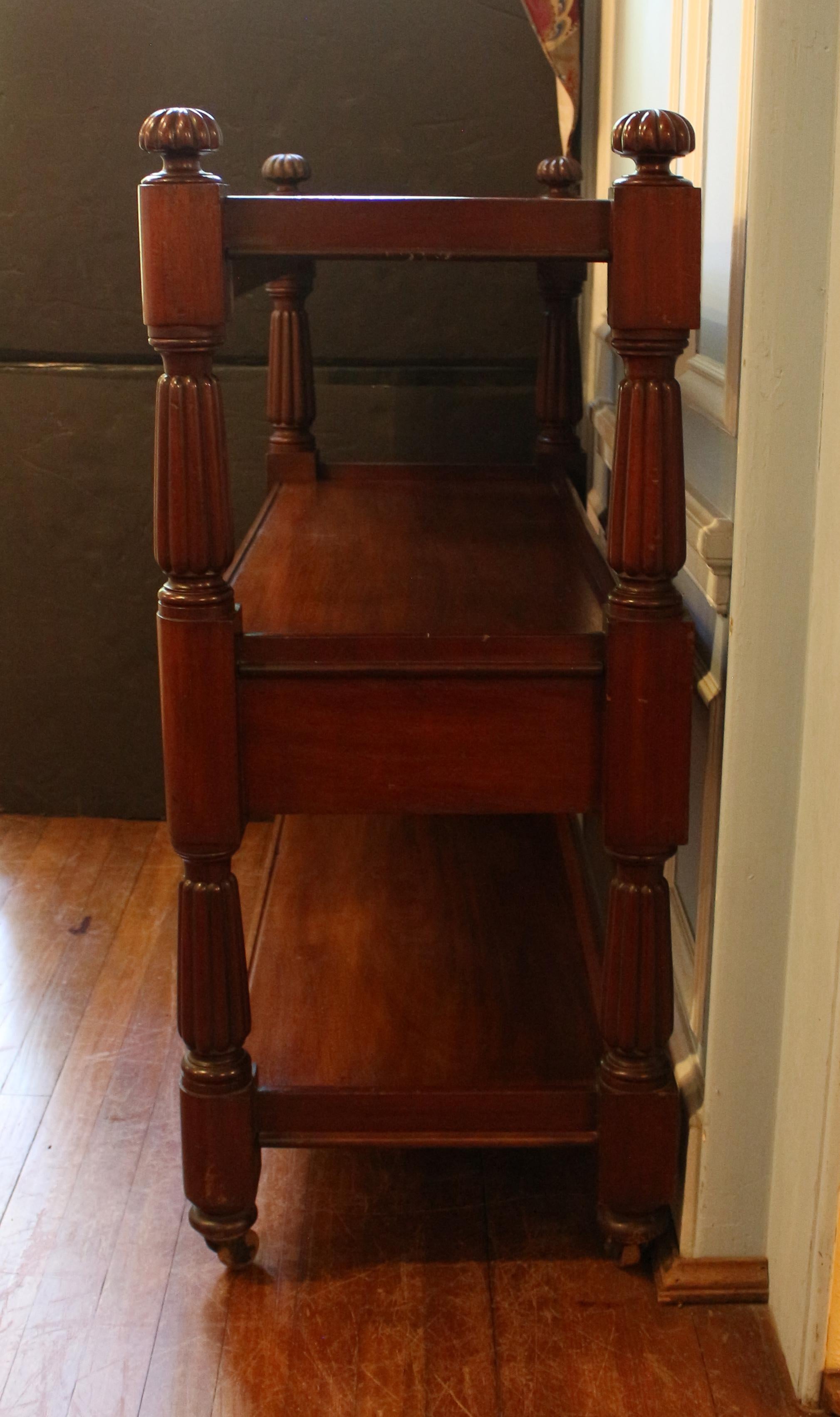 Circa 1830s William IV dumbwaiter trolley or butler's serving etagere, English. Fine mahogany timbers. Bold, inverted, tapered, gadrooned columns and conforming flattened finials. Galleries for each of the three tiers; the middle tier with two