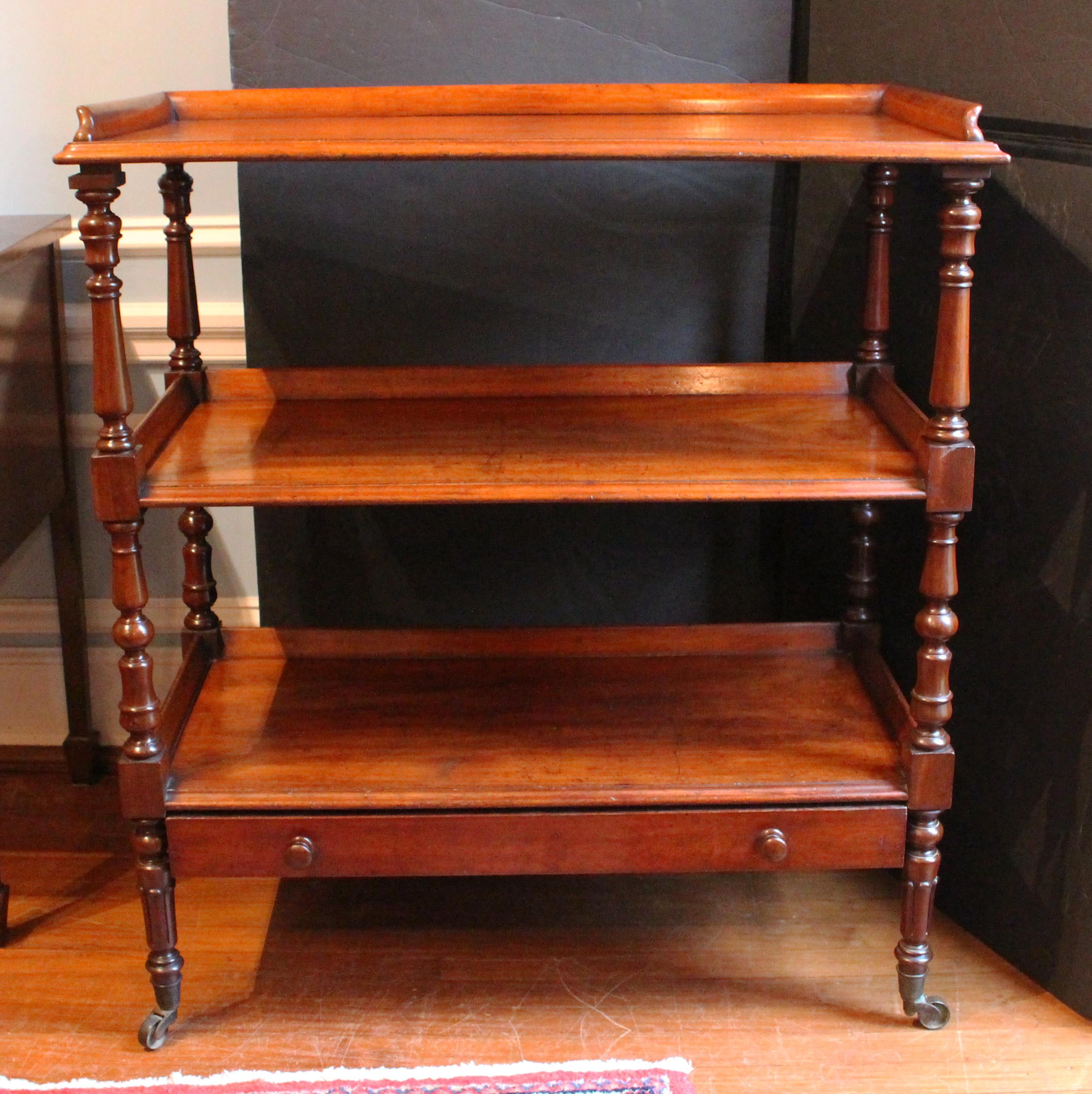 Circa 1835 William IV period butler's trolley etagere or dumbwaiter, English. A handsome example of solid mahogany. Three galleried tiers gracefully outswept. Well turned uprights create visual interest & lift as the turnings vary upward; ending in