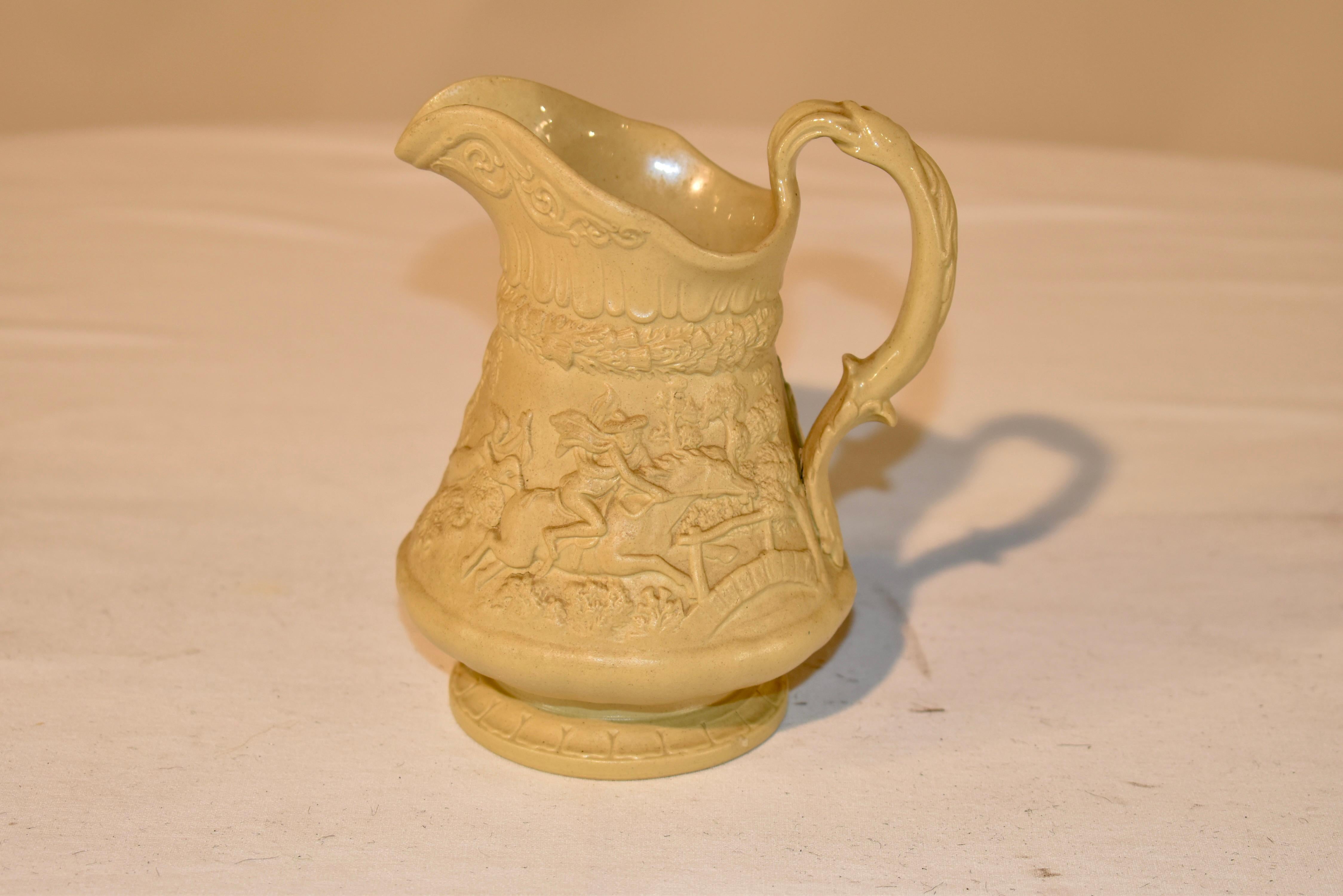 Splendid W. Ridgway & Co. drab ware pitcher which is dated on the bottom with an impressed mark October 1, 1835. This pitcher is in a pattern depicting a village scene including a pub and a horse race outside. The handle is exquisitely molded and